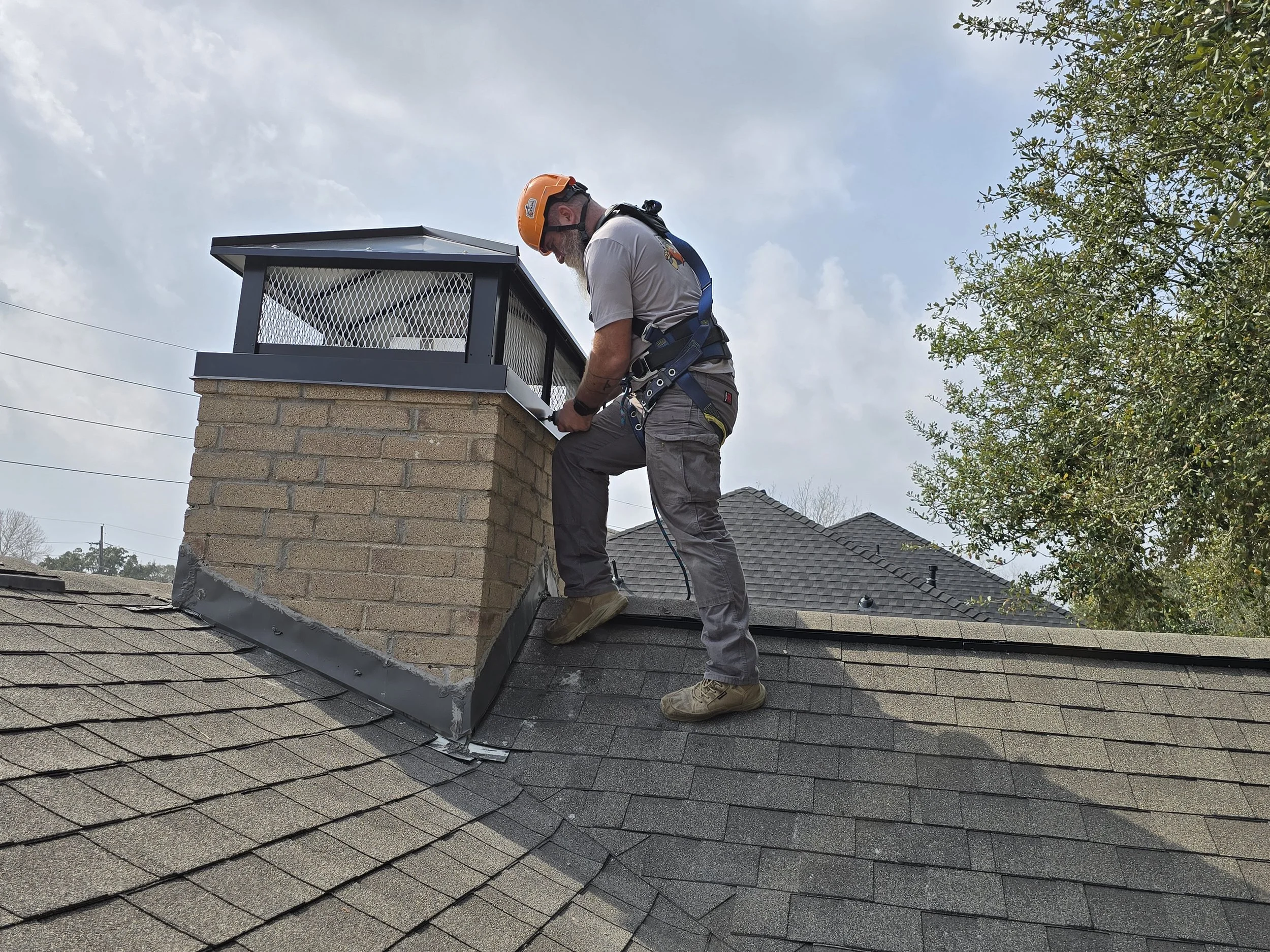 Viking Chimney Solutions installing a black custom chimney cap on a masonry chimney near Sugar Land, Texas