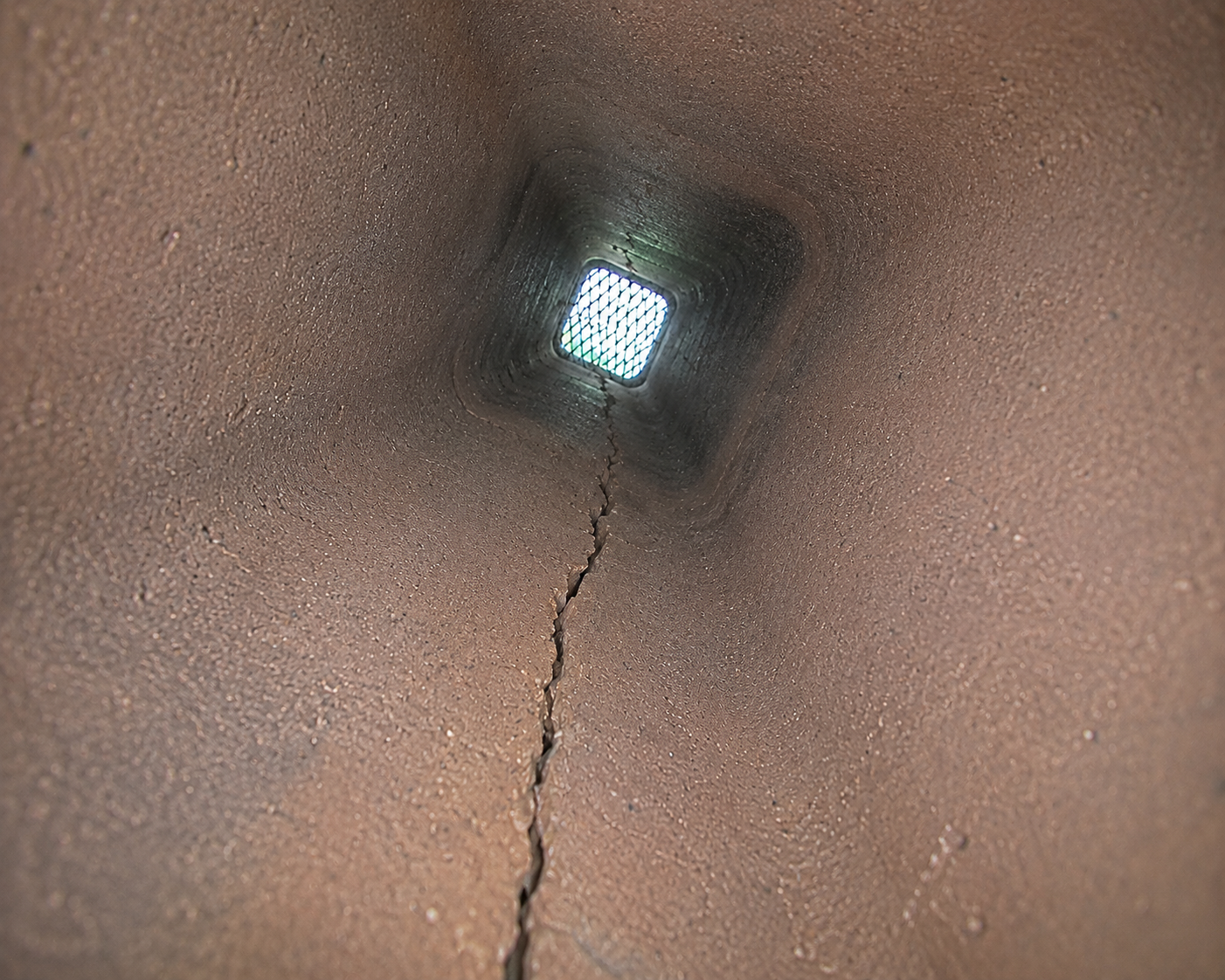 Inside a clay pipe looking up towards the grate at the opening.