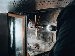 A person using a blowtorch to work on a metal object in a workshop or garage setting.