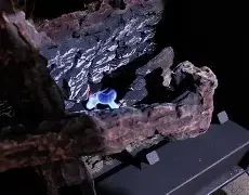A close-up of a rocky surface with some blue light reflections, possibly from a display or screen, in a dark environment.