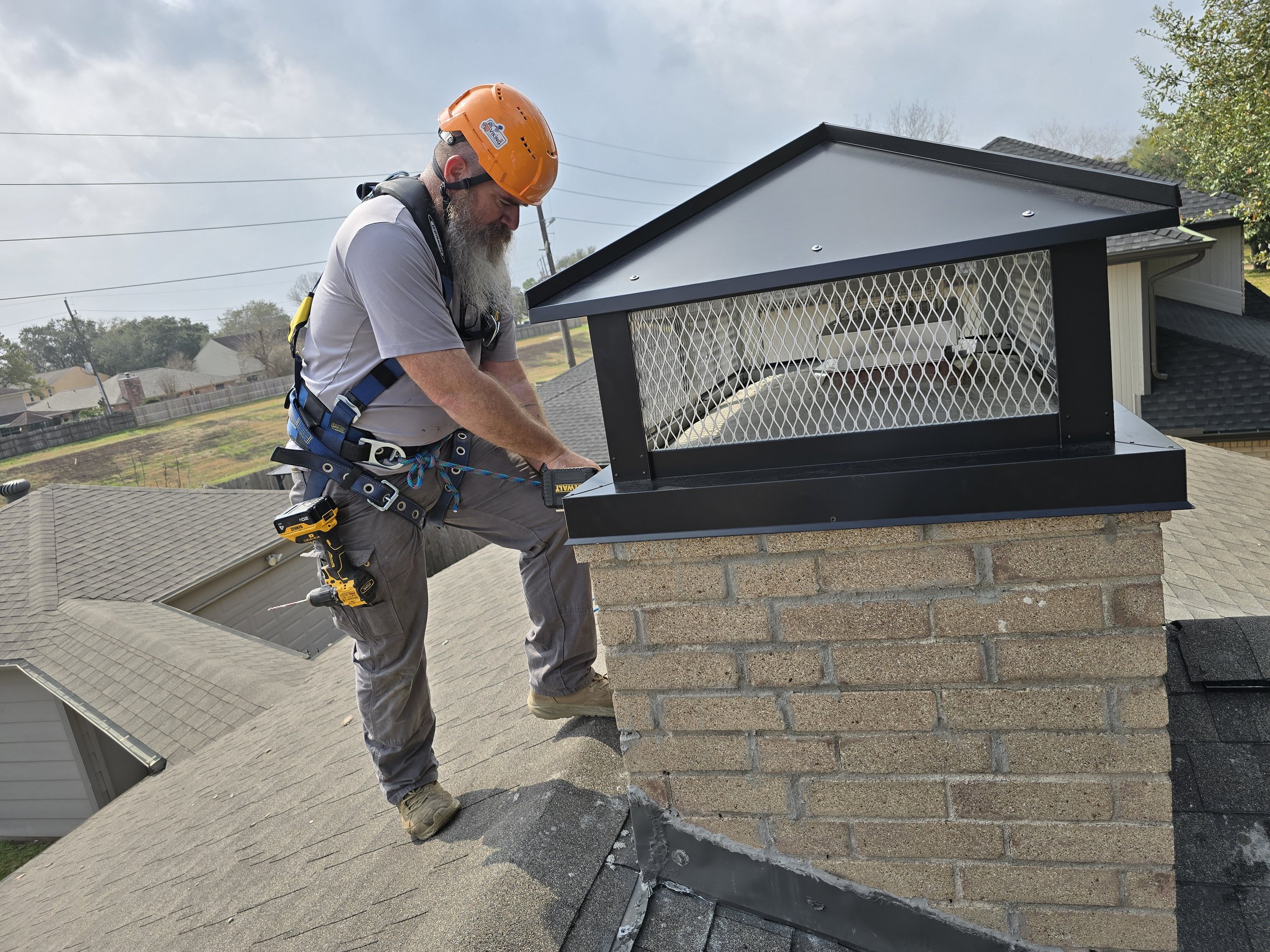 Certified chimney technician installing a custom chimney cap on a masonry chimney in Southeast Texas