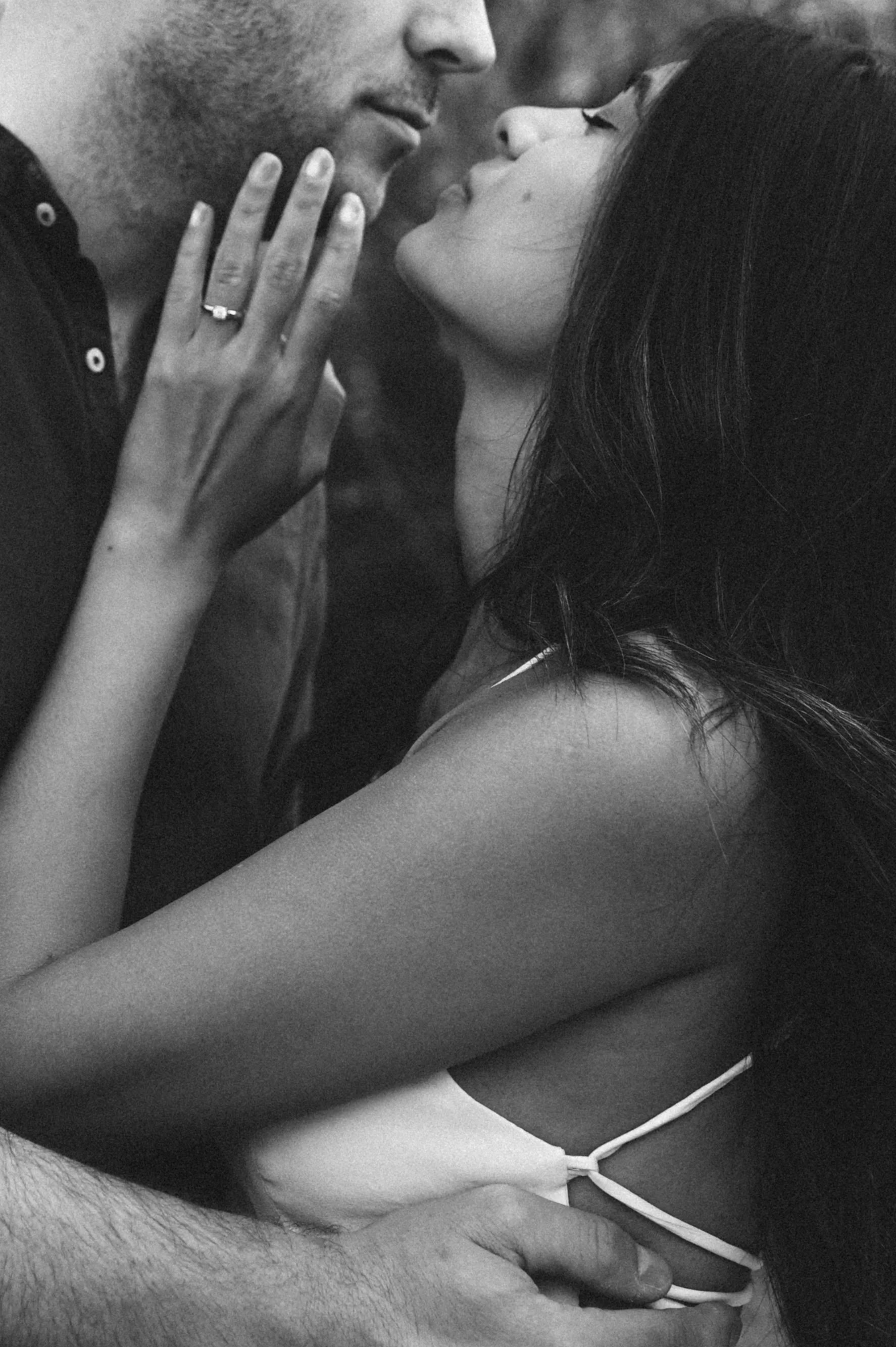 Close-up of a couple about to kiss, with the woman's hand showing a wedding ring on her finger.