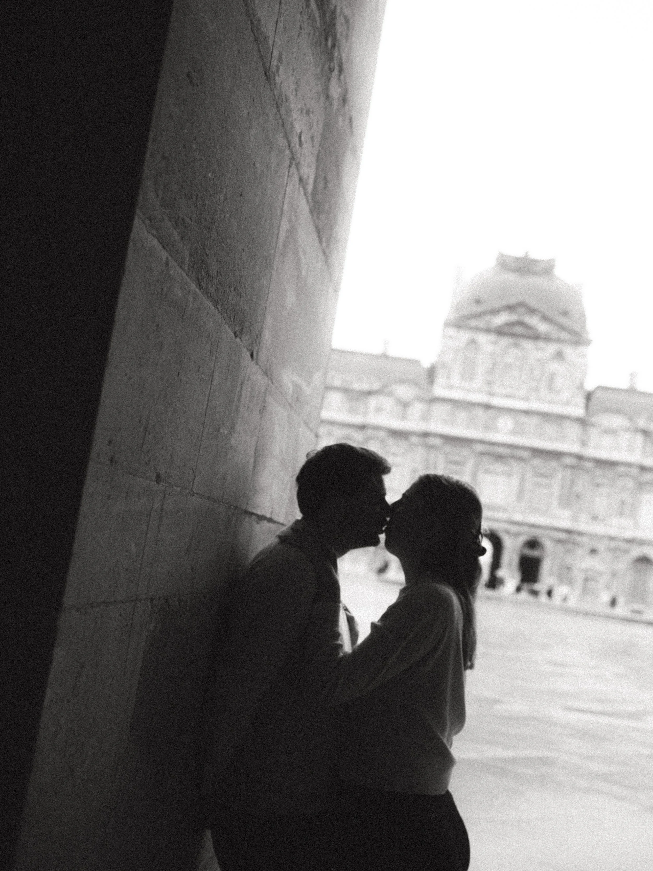 black and white photo of a couple kissing in Louvre surroundings