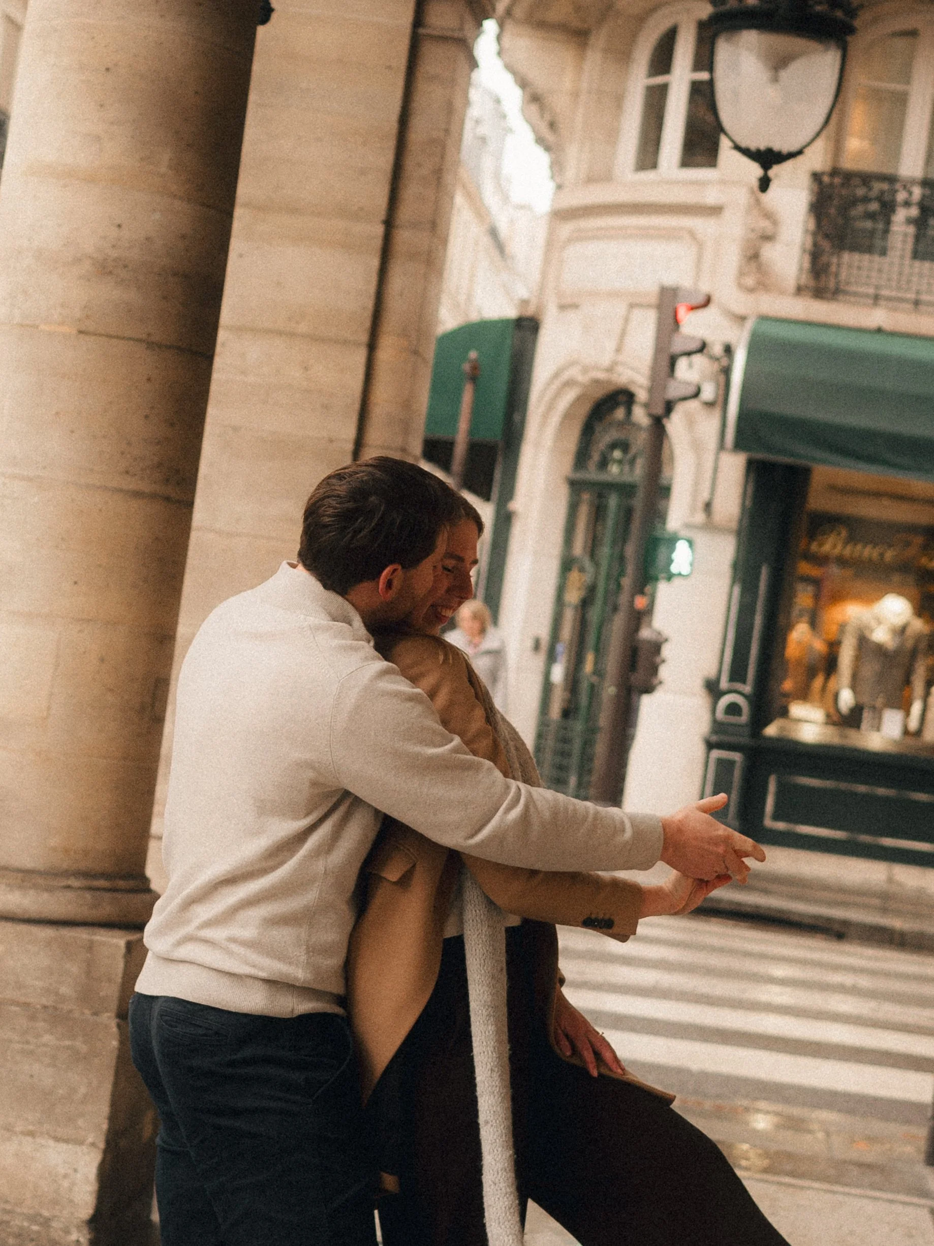 A man and woman sharing a joyful hug on a city street at dusk.