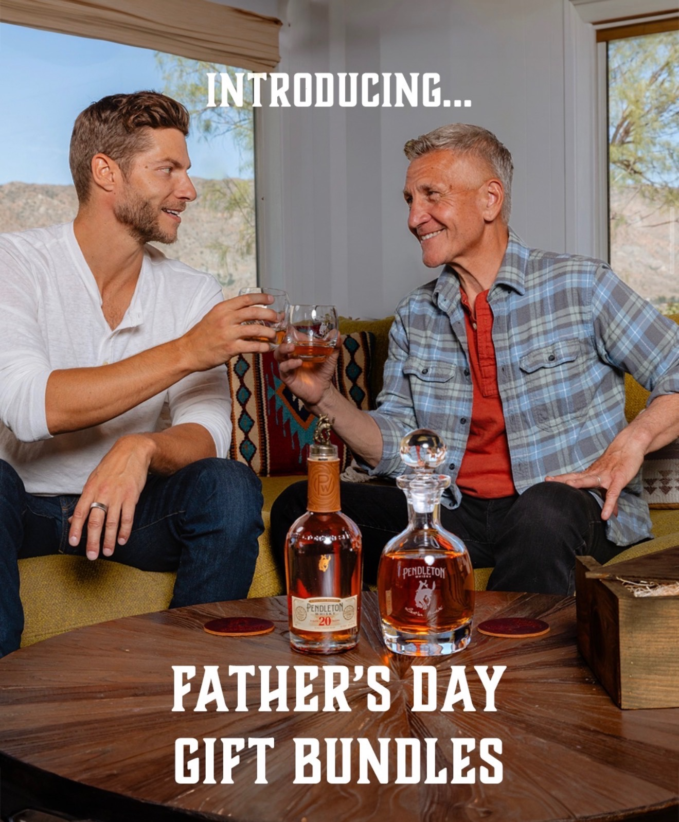Two men toasting with glasses of whiskey in a living room with large windows, bottles of Pendleton whiskey on the table, and a sign that reads "Father's Day Gift Bundles".