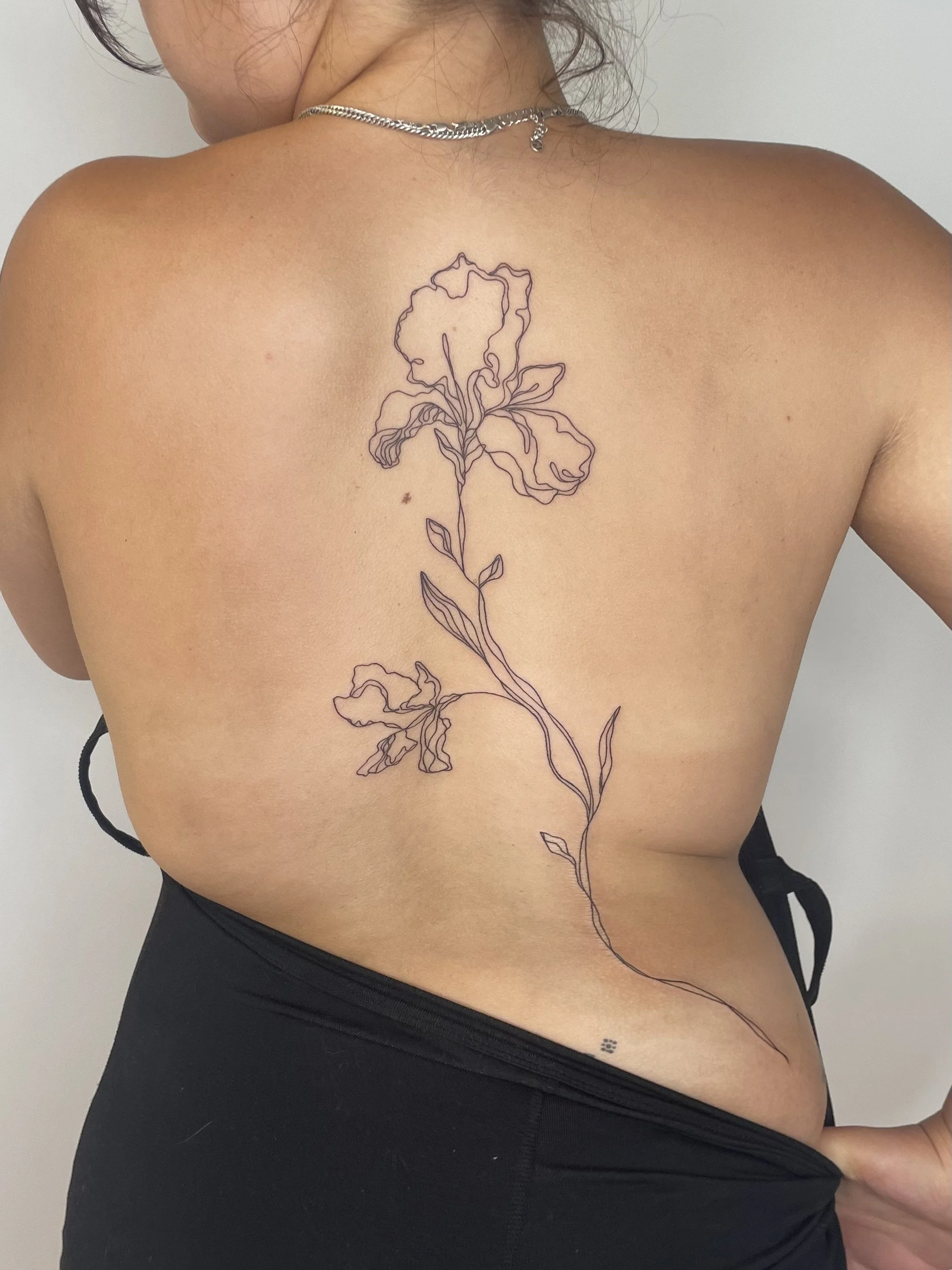 Tatouage d'une fleur stylisée en ligne fine sur le dos d'une personne