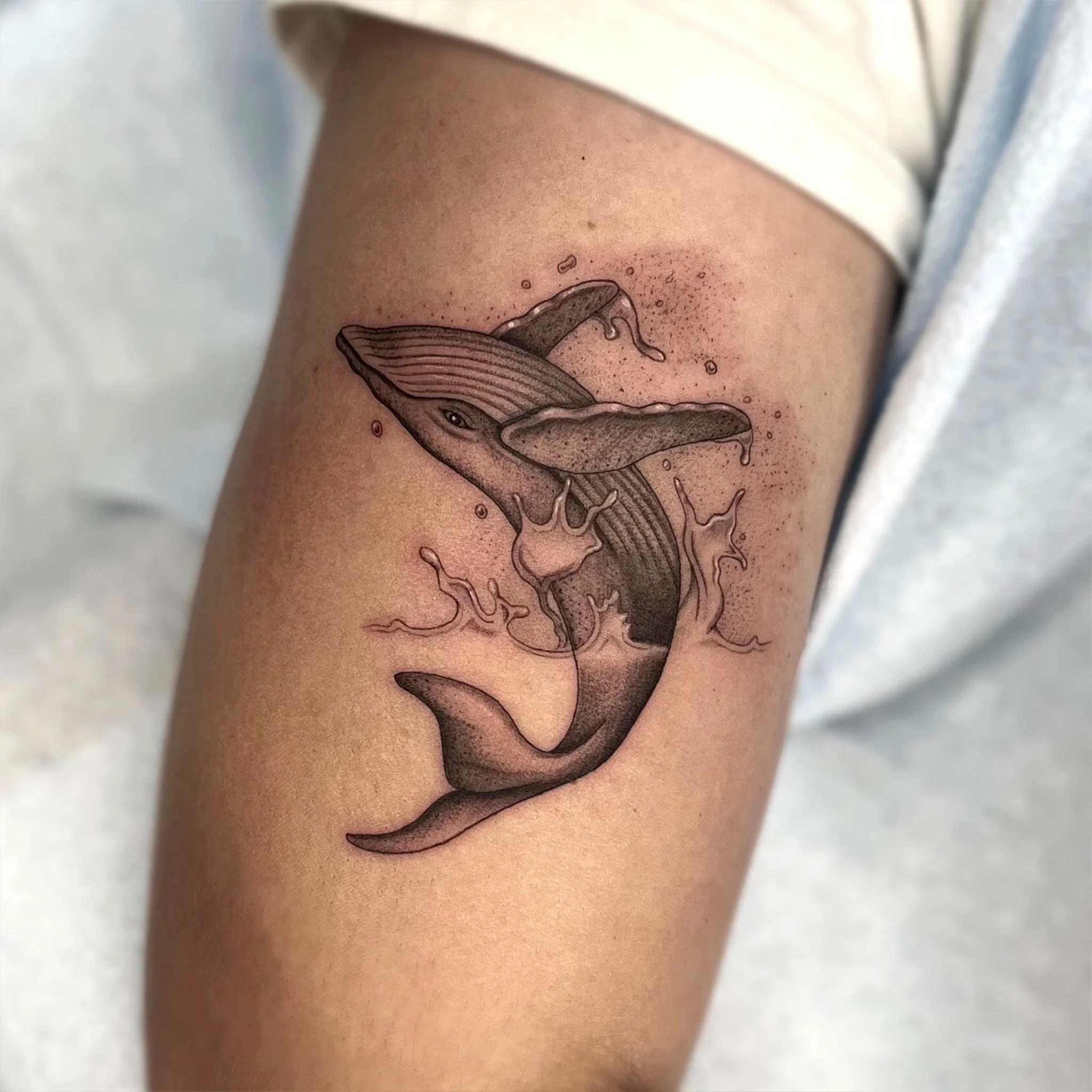 Tatouage d'une baleine illustrée avec un style réaliste, avec des détails et des ombres, sur la peau d'une personne.