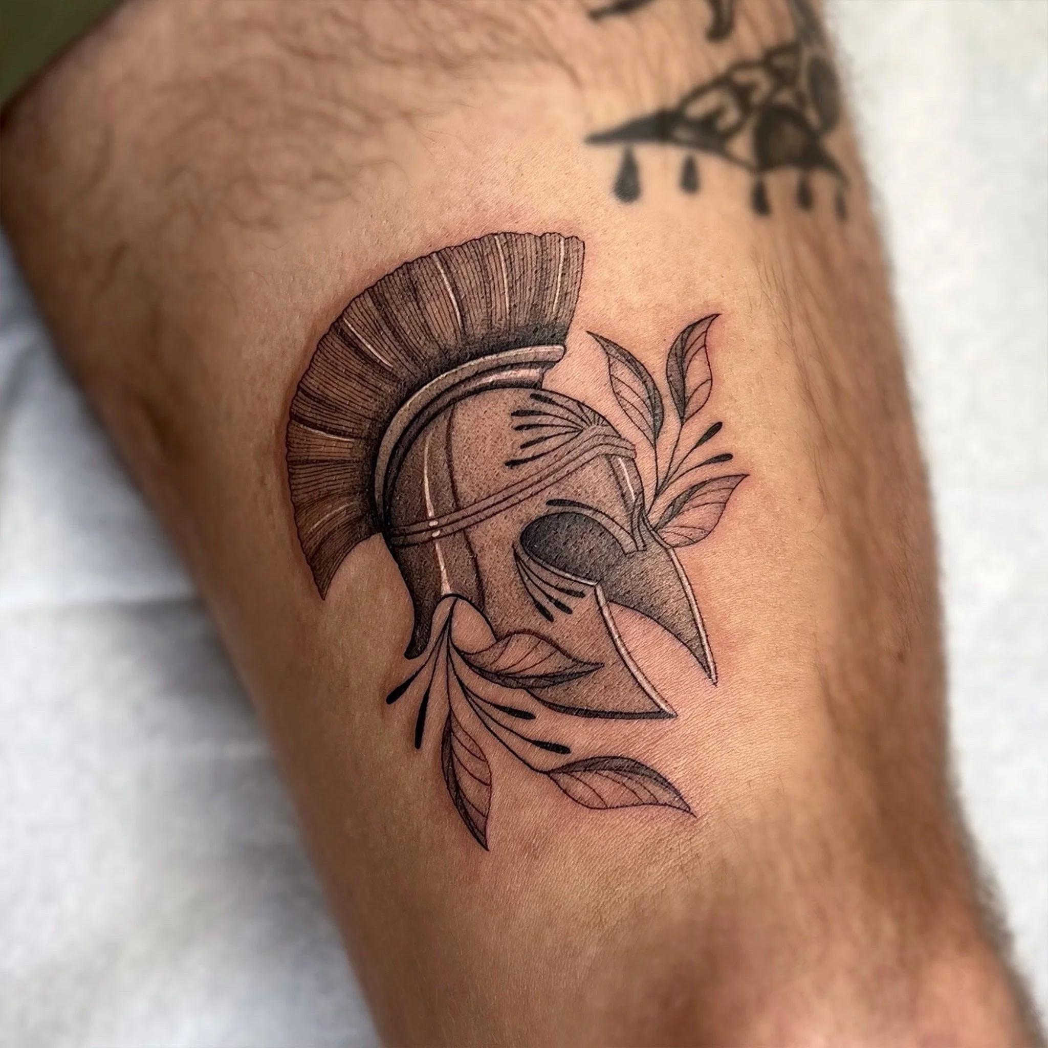 Tatouage noir et gris d'un champignon et de feuilles sur la peau d'un bras.