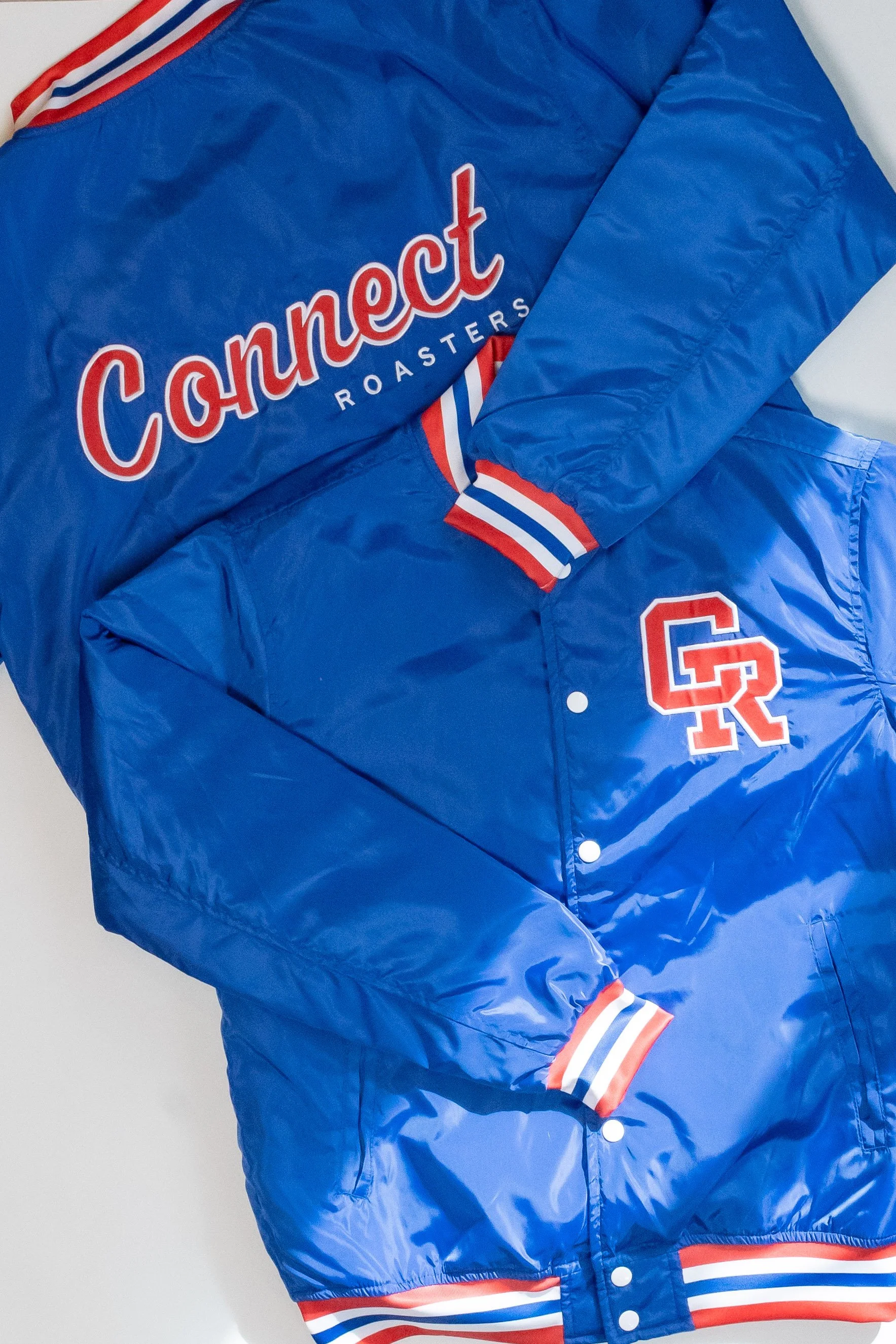 Blue varsity jacket with red, white, and blue striped cuffs and collar, featuring the word "Connect" and the word "Roasters" below it, along with a large letter "G" with a smaller letter "R" inside.