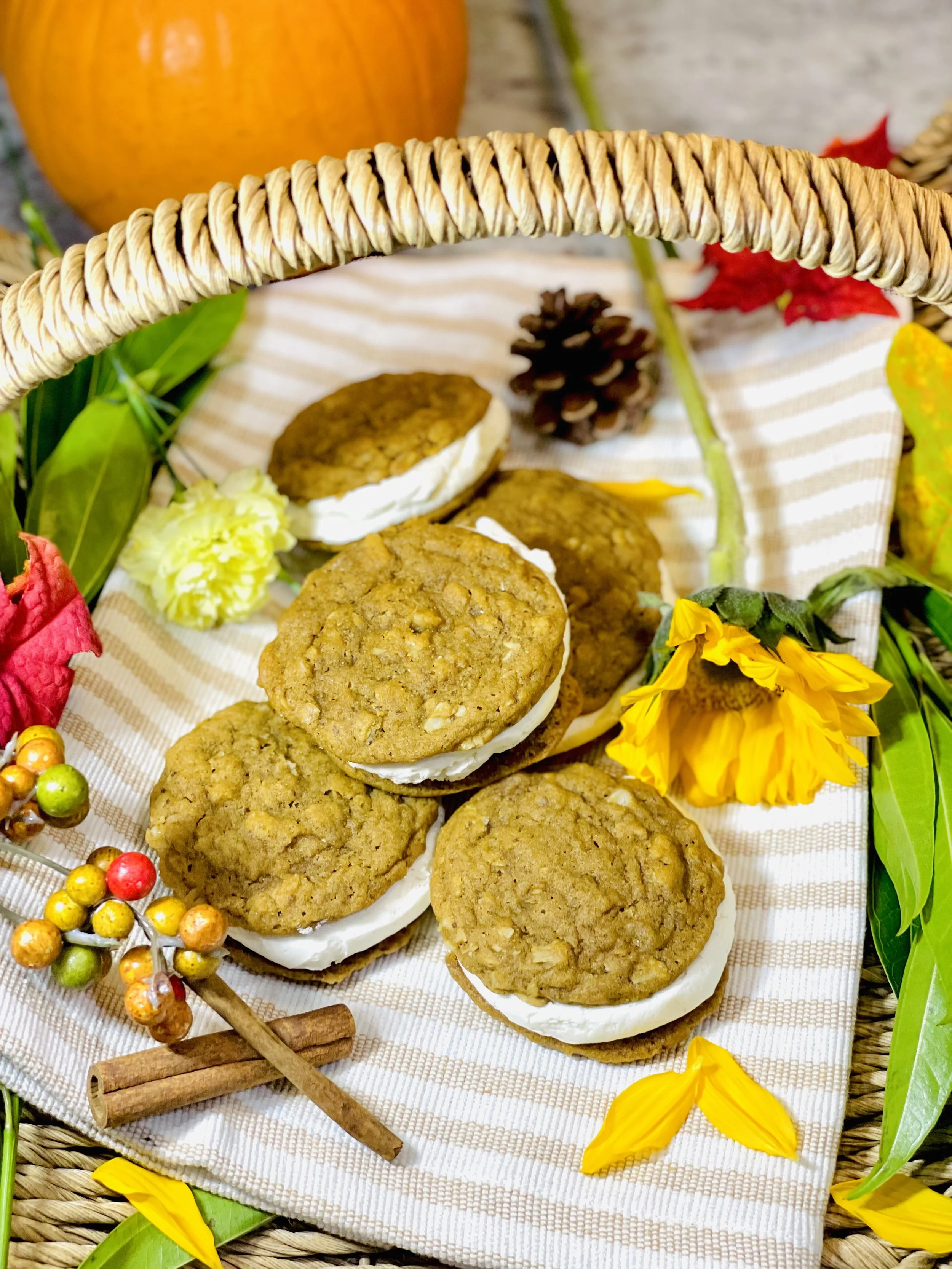 Close-up of Pumpkin Spice Oatmeal Cream Pies stacked in a cozy autumn arrangement with pumpkins and leaves.
