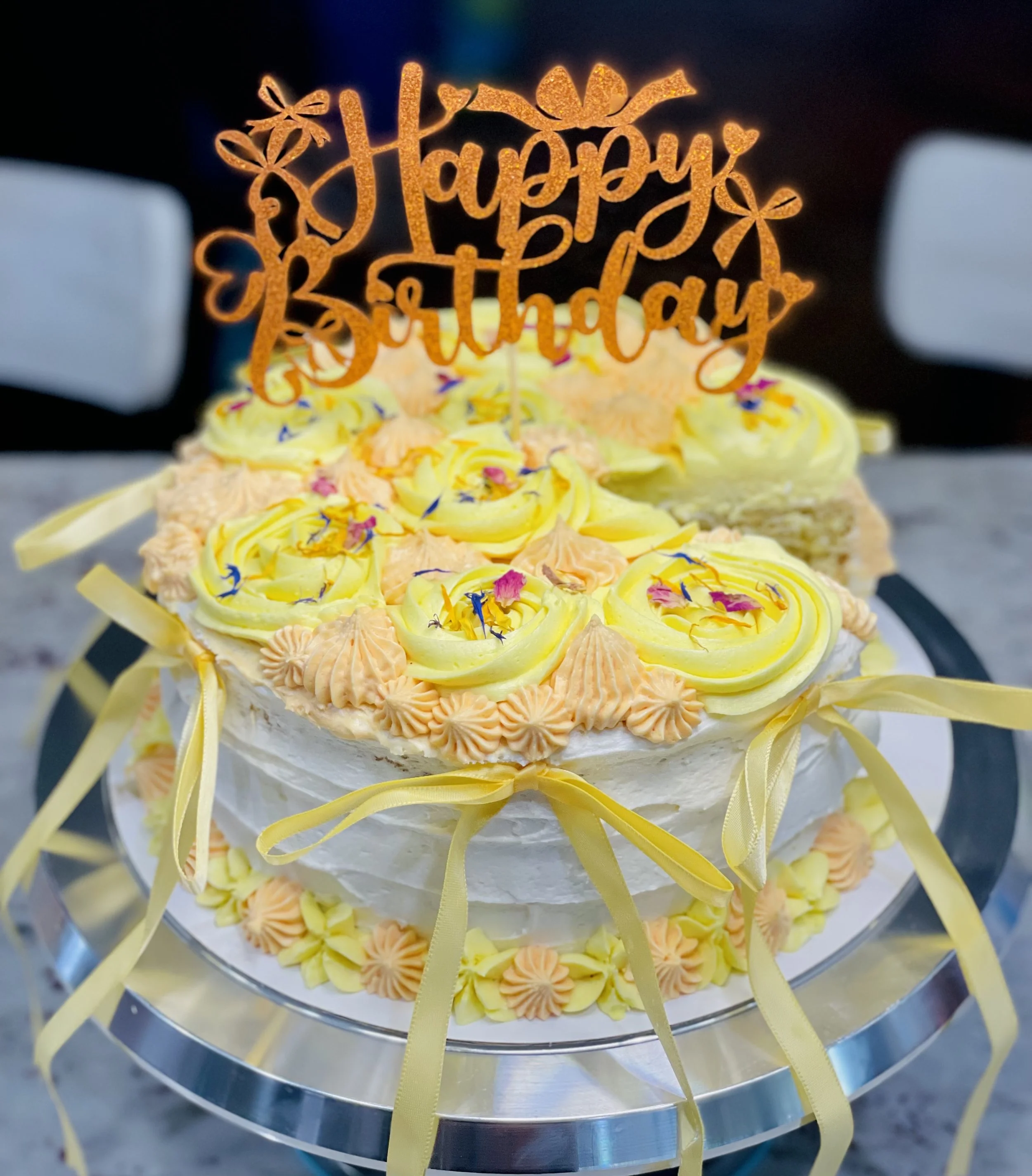 Citrus Blossom Cake from Sunshine & Bloom Bakery – vegan pineapple, coconut, lemon, and orange zest layer cake with lemon curd filling, decorated with yellow buttercream flowers and edible blossoms.