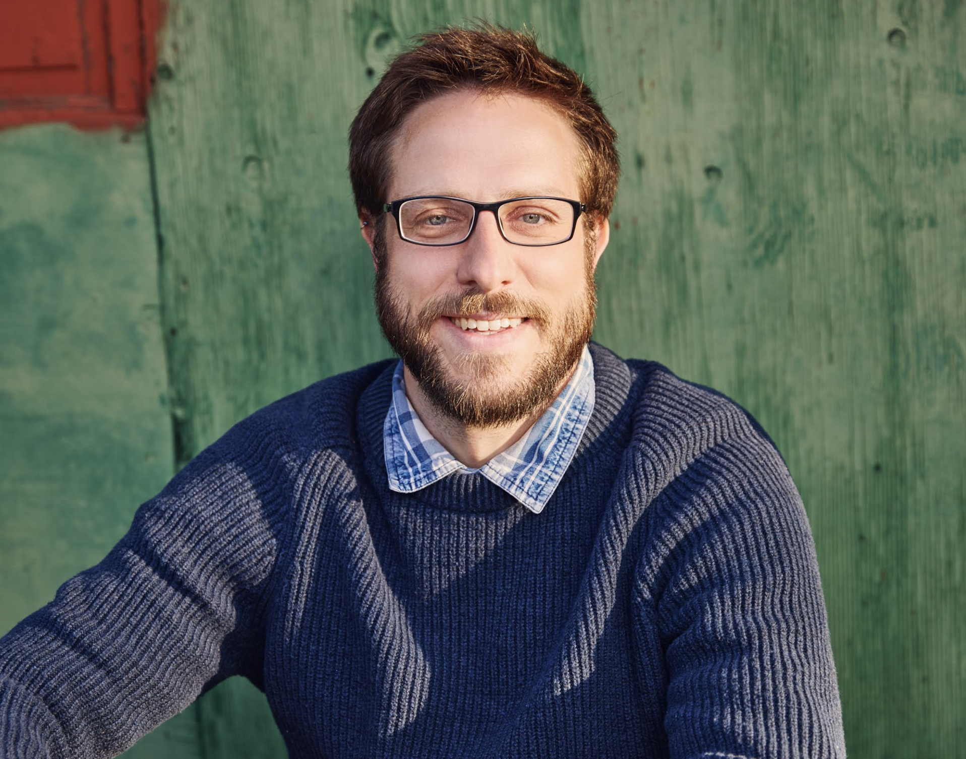 A young man with glasses, a beard, and brown hair