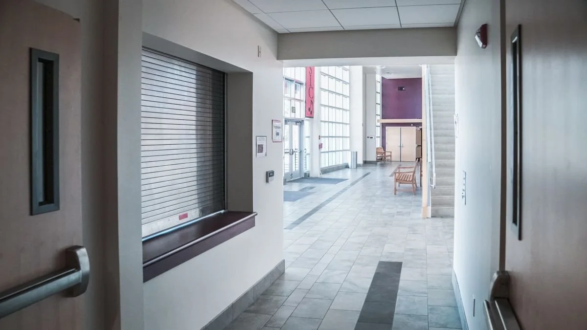 Empty lobby area with chairs, stairs, and large glass windows in a modern building.