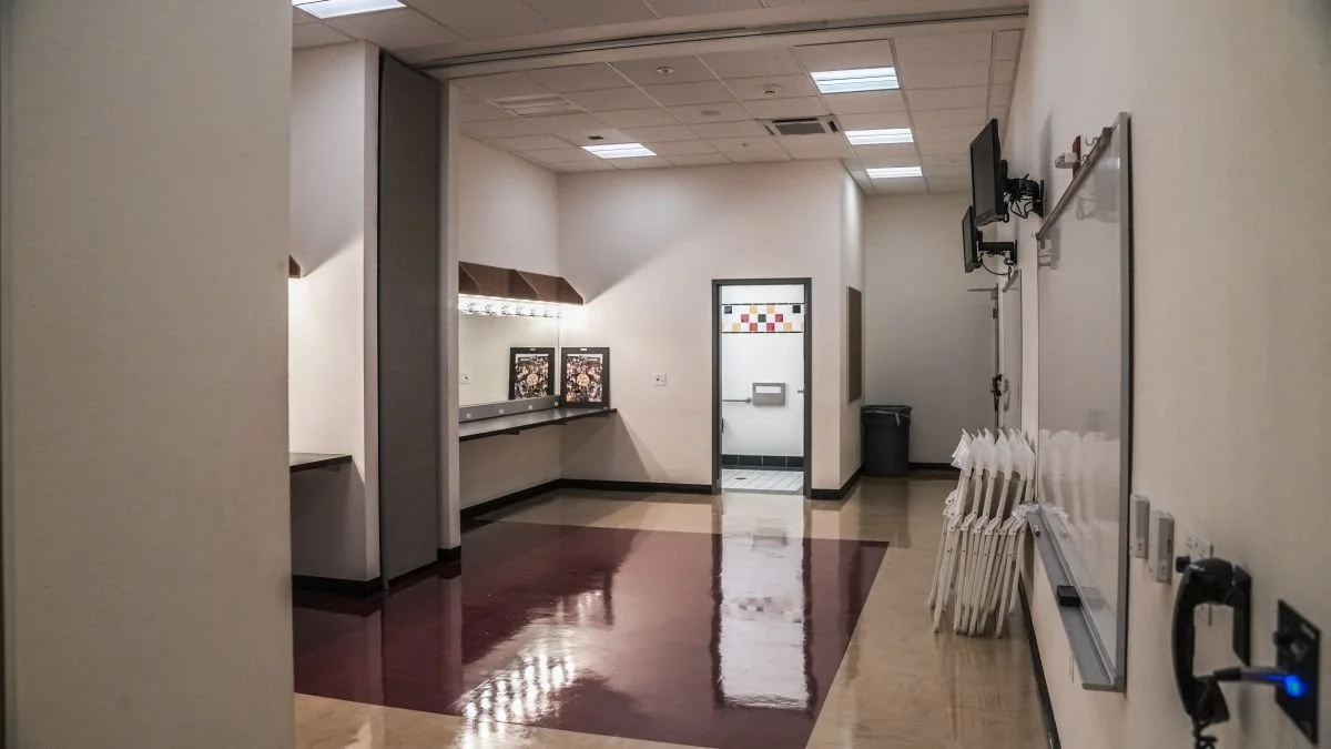 Empty school classroom or conference room with chairs stacked, whiteboard, and wall-mounted monitors