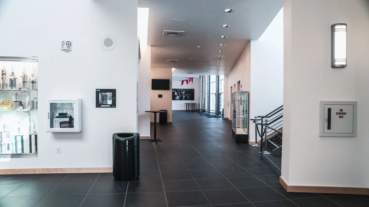 Empty indoor space with display case, trash can, fire safety equipment, and windows