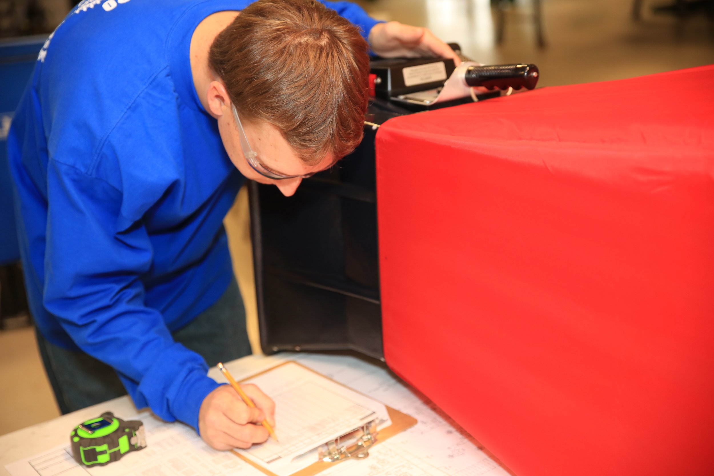 A man with a beard wearing a brown beanie smiling while working on an HVAC 
