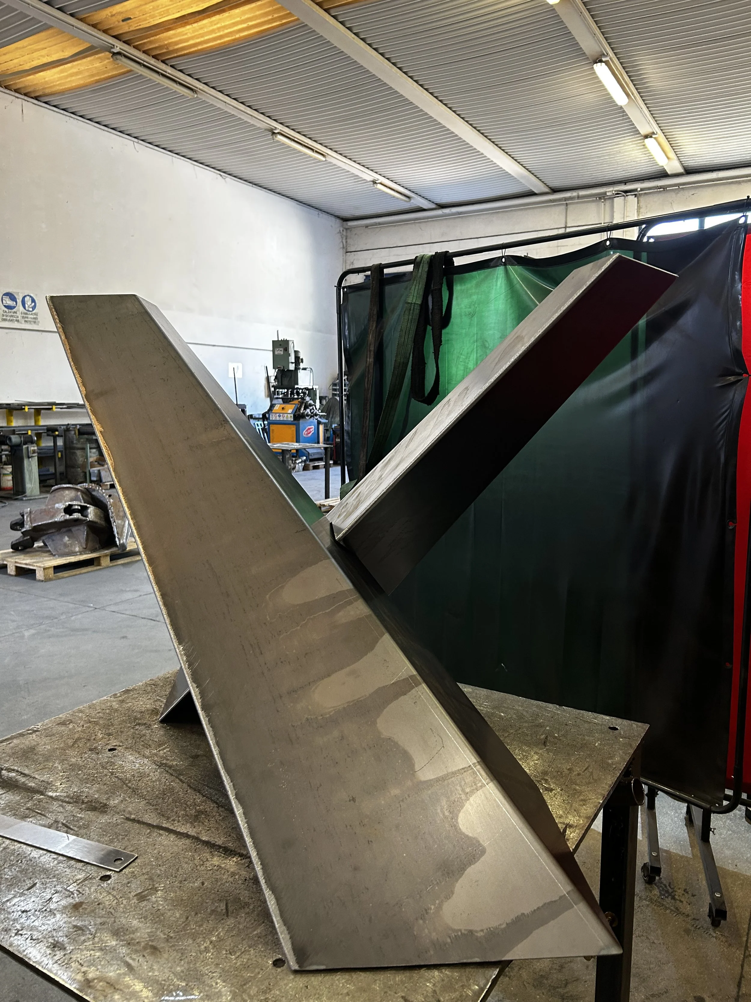 Un'installazione industriale con grandi lastre di metallo inclinate su un banco di lavoro in un'officina.