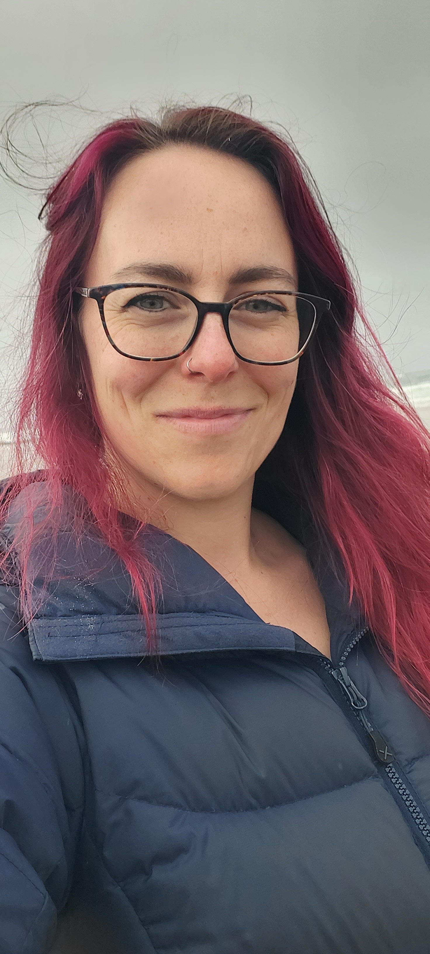 Counsellor, Cassie Hogg, with red hair and glasses smiles outside