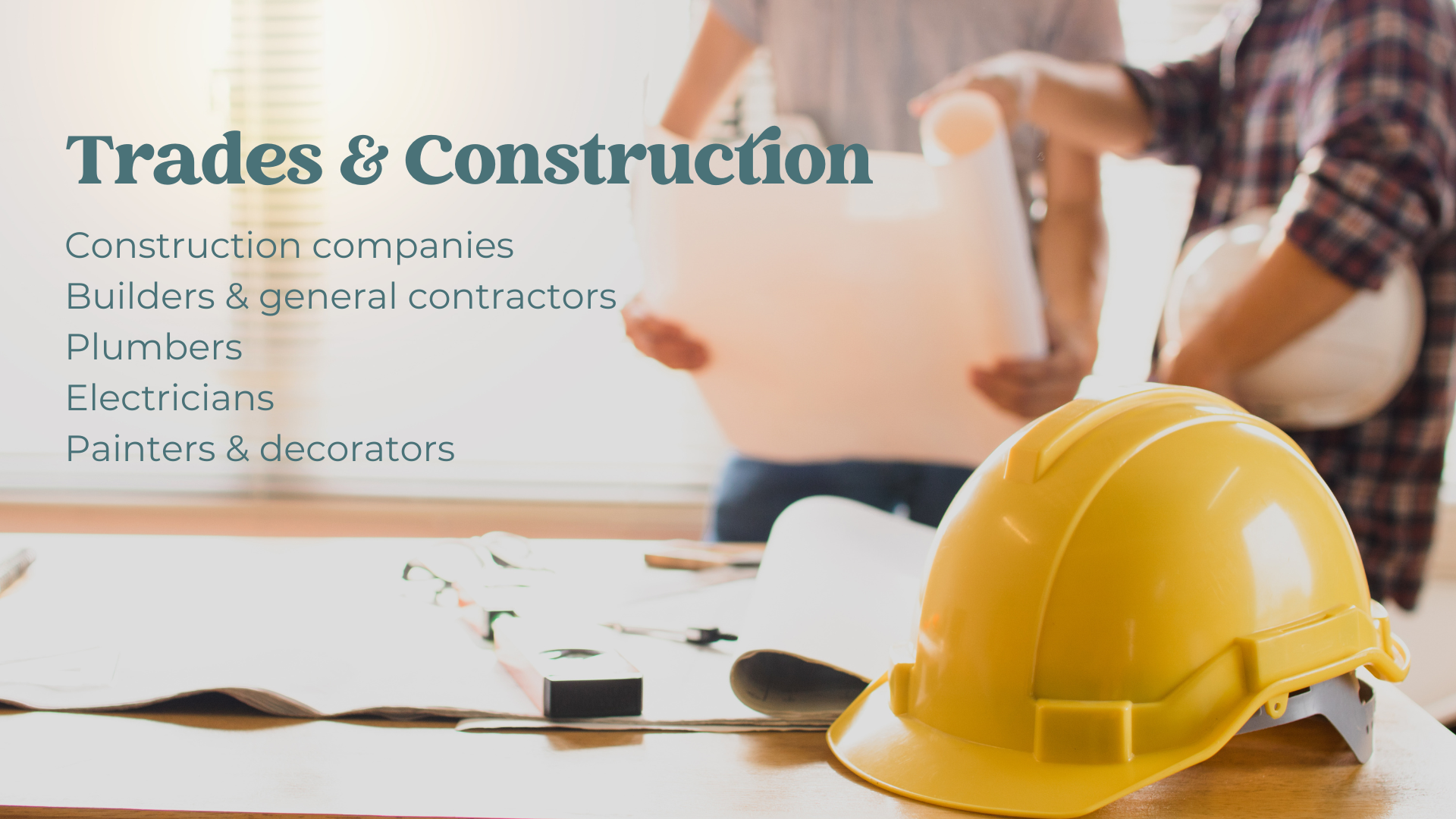 A yellow construction helmet on a table with a blueprint and construction tools, with two people in the background reviewing plans, representing trades and construction.