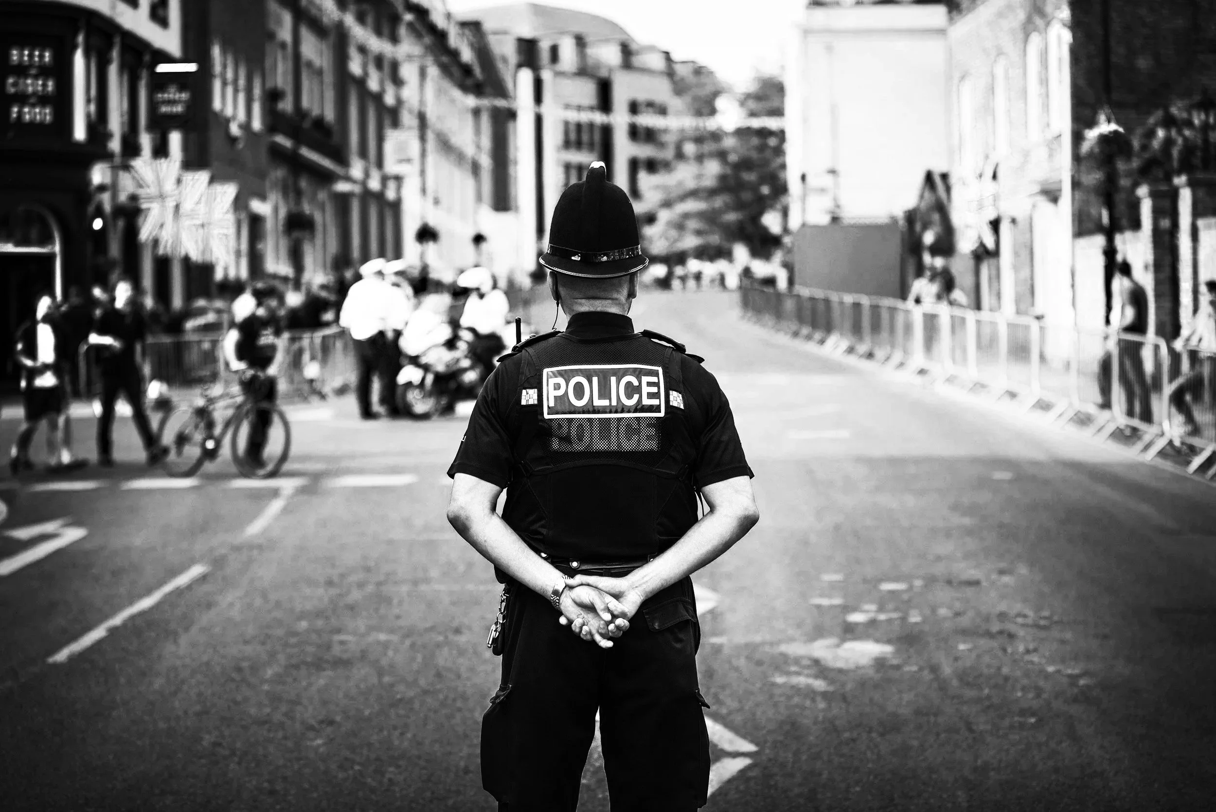 A police man in a British police uniform stands with his back to the camera