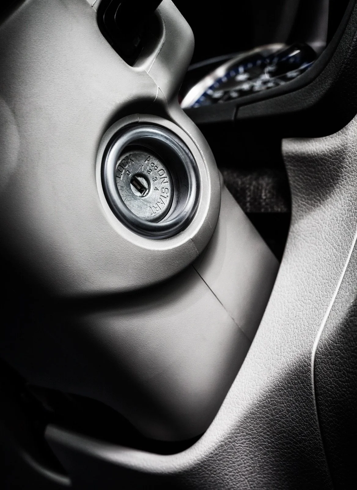 Close-up of a car ignition with a key inserted, showing the start/lock switch about to be turned.