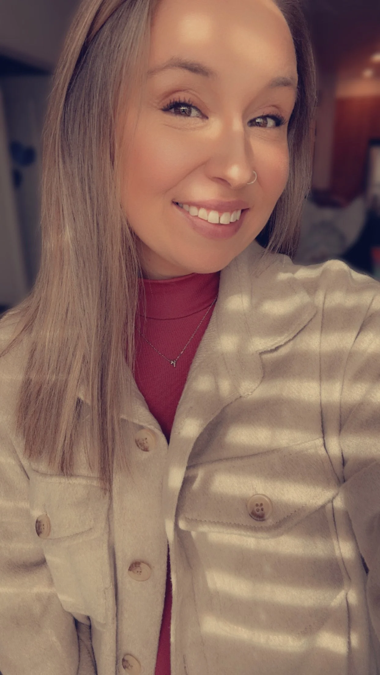 A young woman with blonde hair, wearing an olive green T-shirt with a graphic of a rifle and the text 'Hosen Professor Apparel,' smiling at the camera.