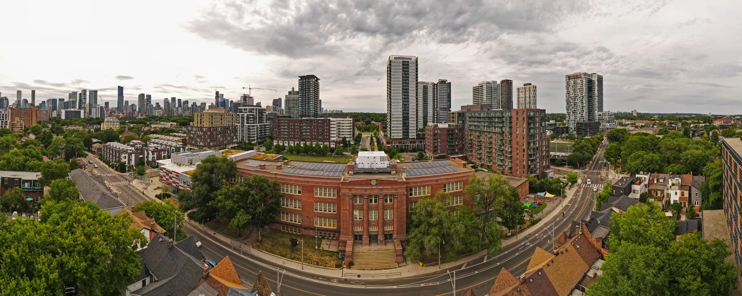 "180° panoramic view of Nelson Mandela Park Public School, capturing its architectural form and surrounding urban context in a sweeping composition that reflects the heart of the community."