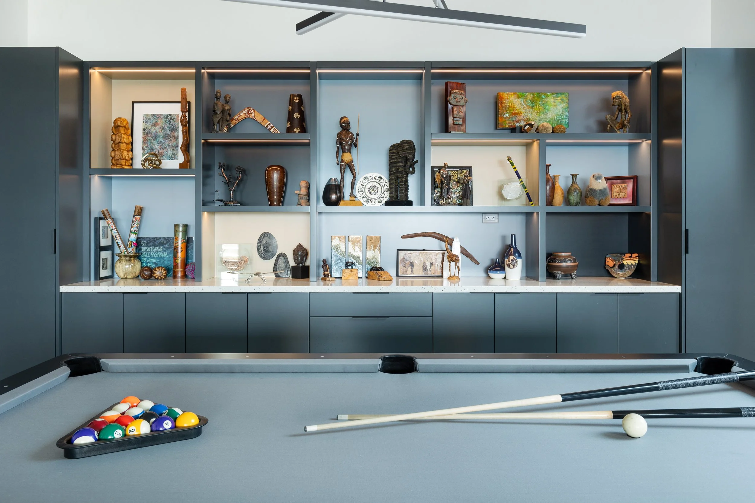 Indoor room with a pool table and decorative shelves filled with various art and decorative items.