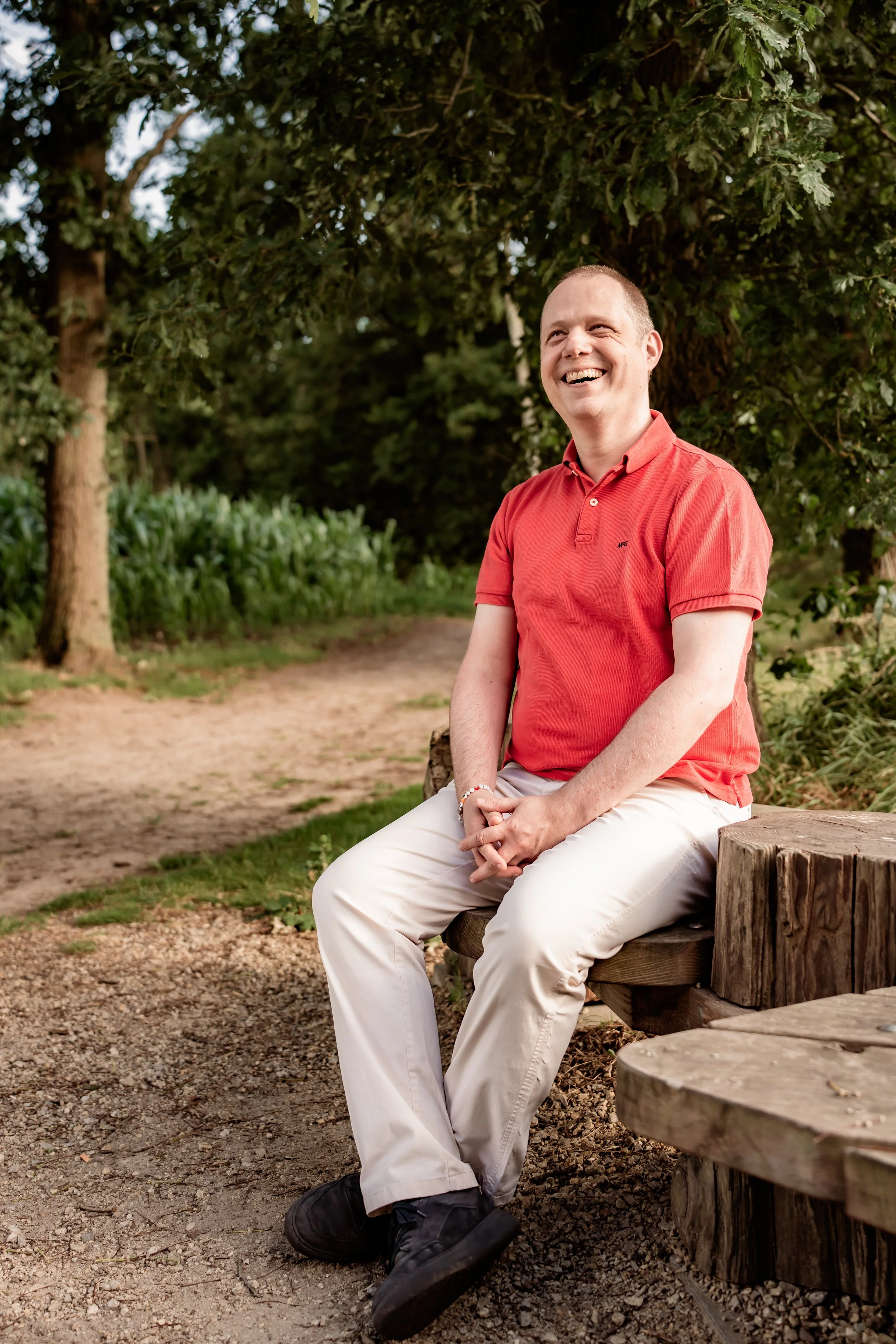Maarten Wauters, zittend op een houten bank in een natuurlijk bos, straalt rust en helderheid uit als begeleider van het Quantum Bridge traject voor ondernemers.