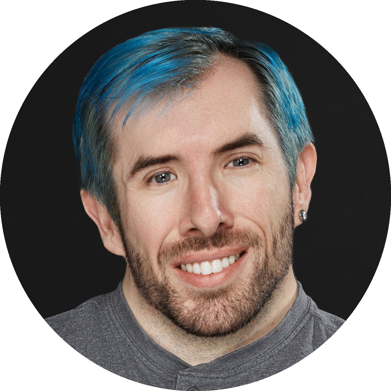 Eric Ingram, co-host of the 0g-SPOT podcast, smiling in a professional headshot with short blue hair and light facial hair, wearing a gray shirt and small earring against a dark studio background.