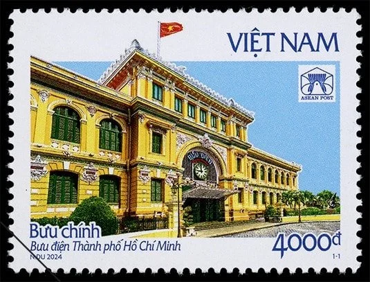Vietnamese postage stamp featuring the Ho Chi Minh City Post Office building with a yellow facade, green window shutters, and a flag of Vietnam.