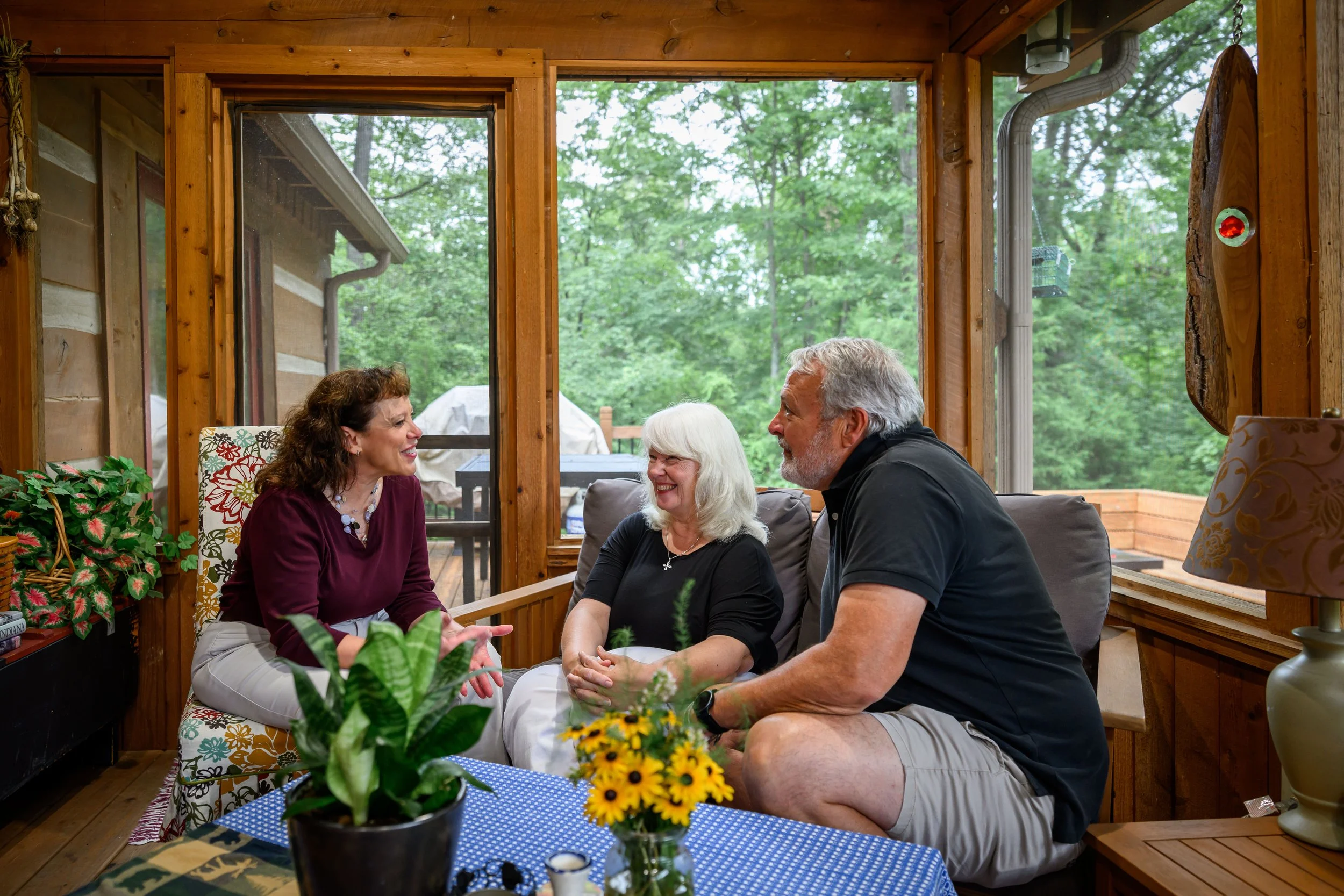 Amy Huffman Oliver speaks to a couple in a screened-in porch.