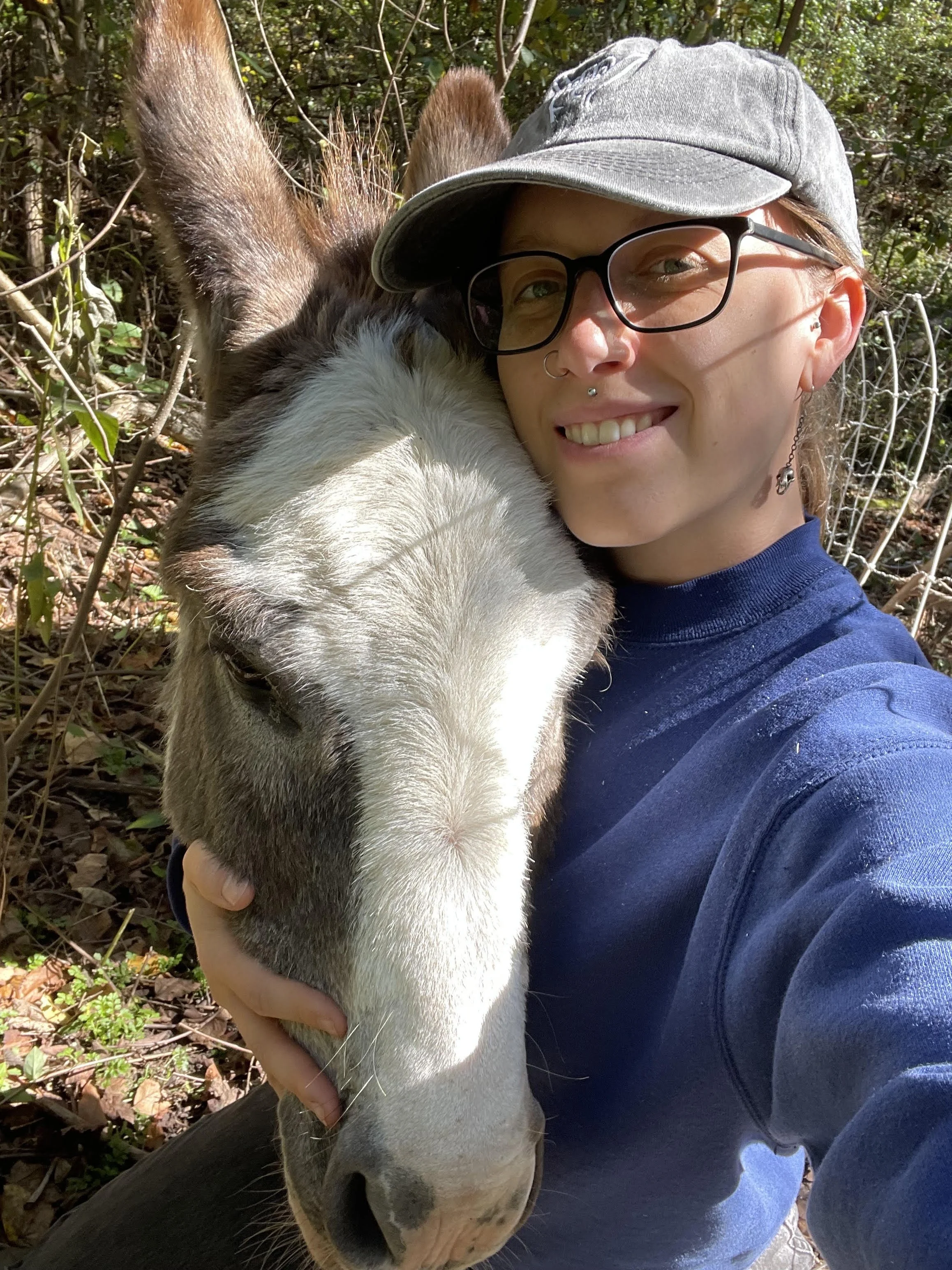 Rhi and Pete smiling as they hug in a wooded area.