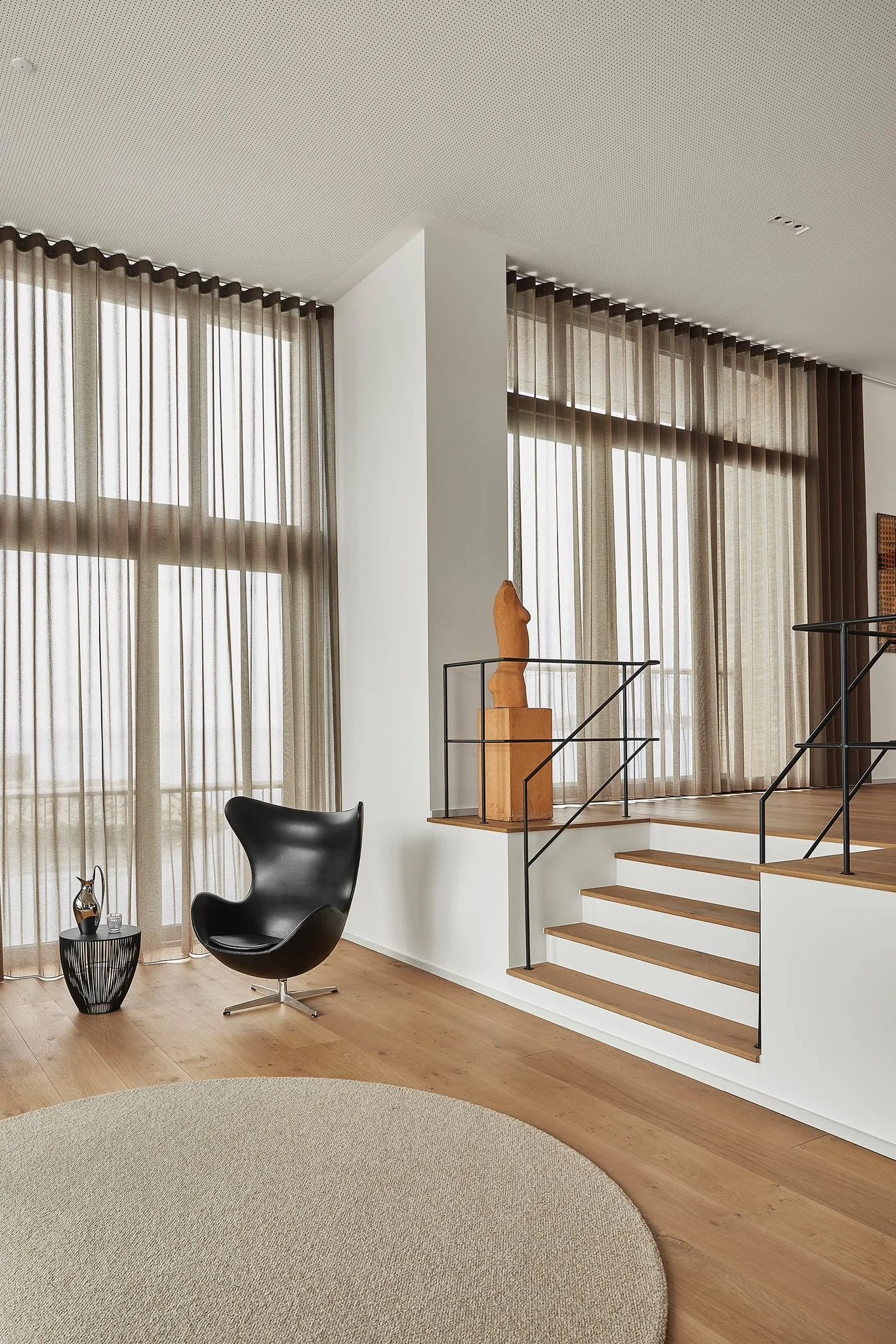 A modern wooden house with large glass windows in a mountainous landscape with brown and green grass in the foreground.