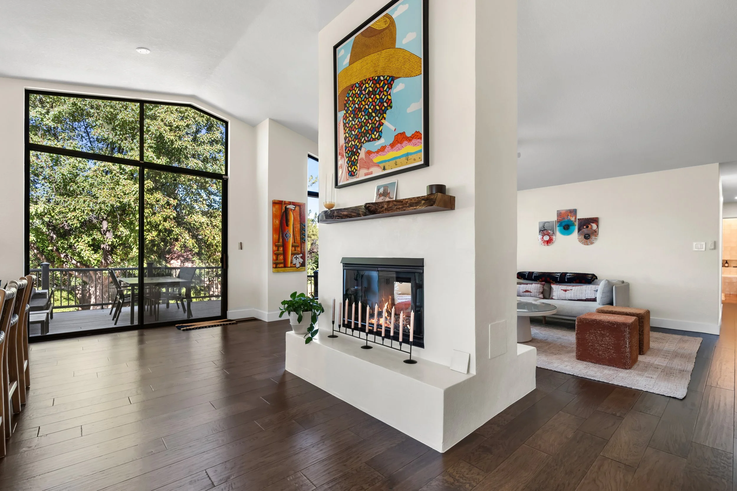 Living room with a fireplace, large glass sliding door leading to a balcony, modern art on the walls, and a cozy seating area.