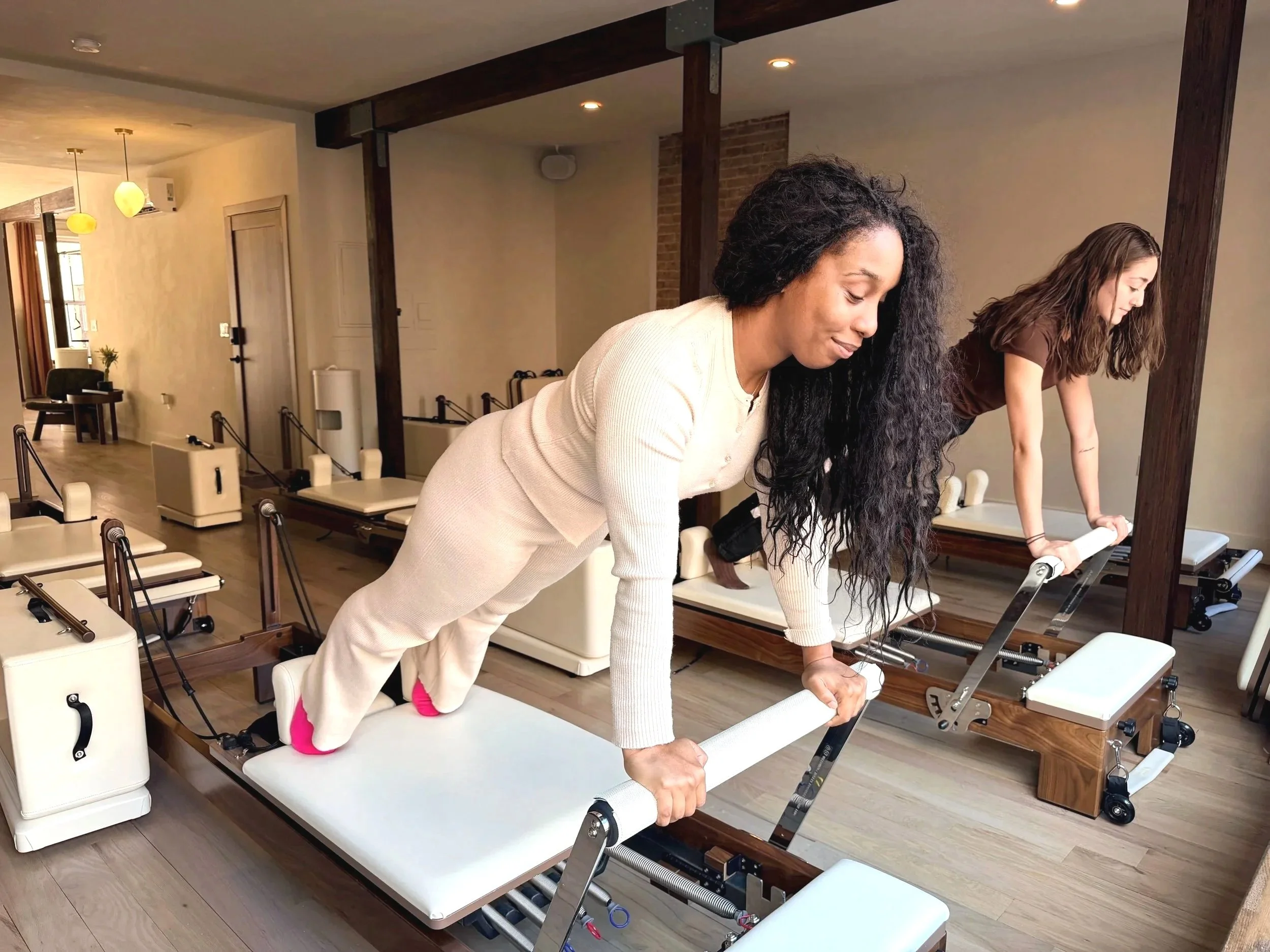 Jae and Kai Pilates reformer semi privateat KIN Kollective Brooklyn, focusing on deep stretching, mindful breathing, and relaxation.