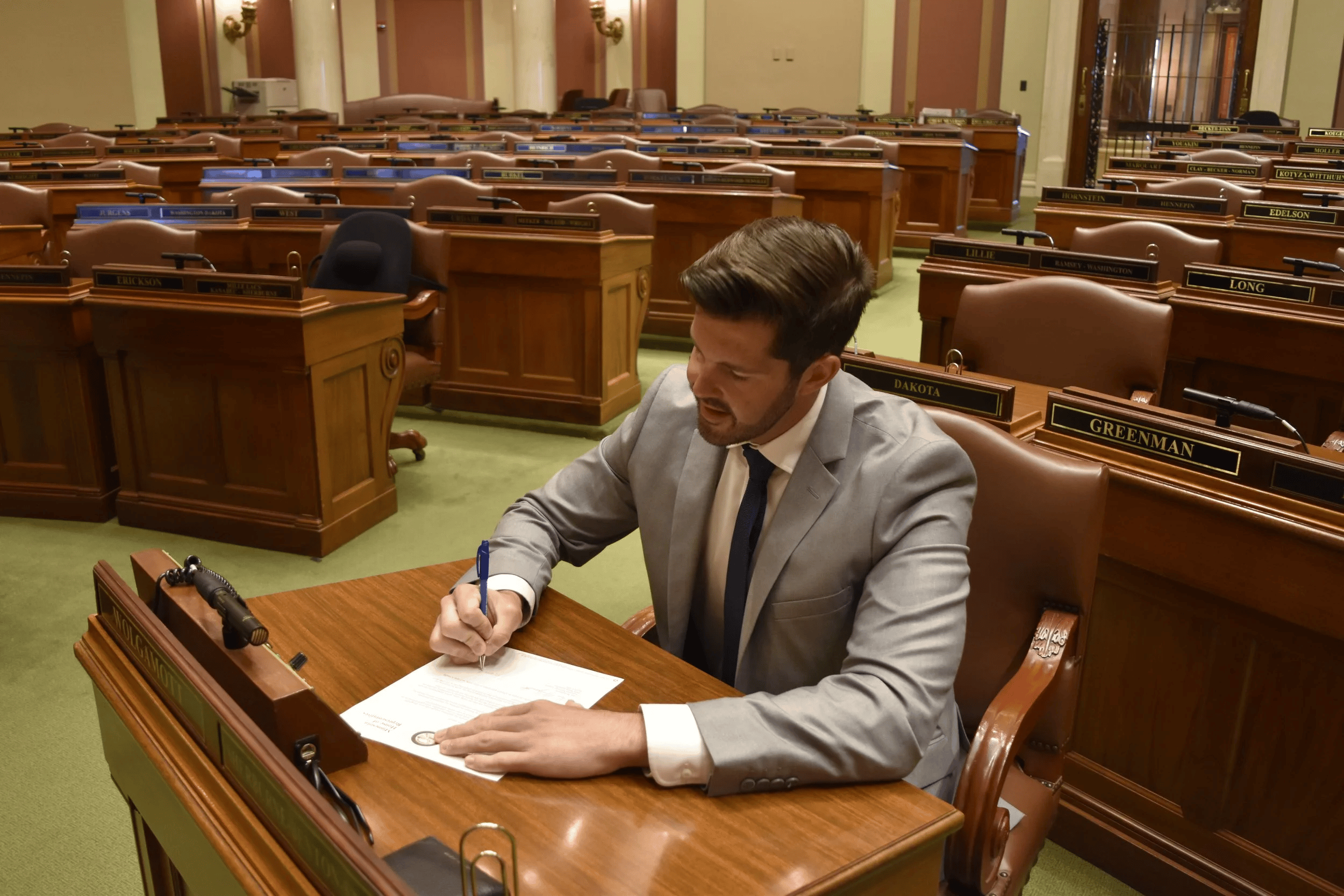 Dan signing his name to legislation at his desk on the House floor