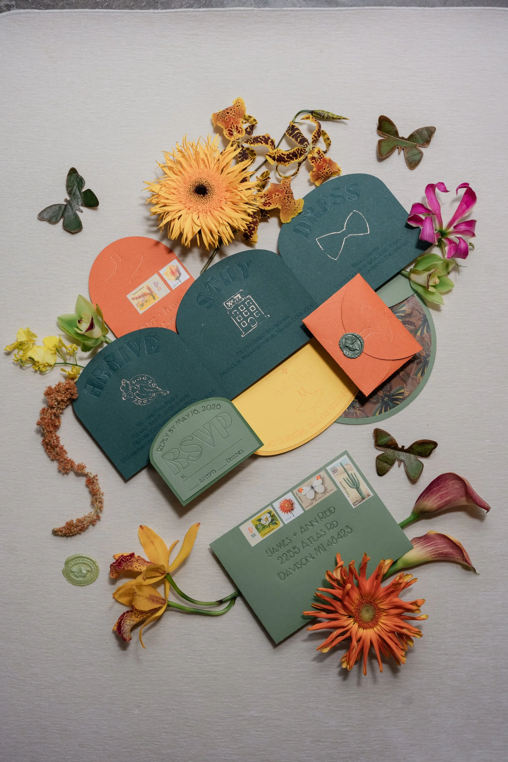 A flat lay with wedding invitations small florals, and jewelry