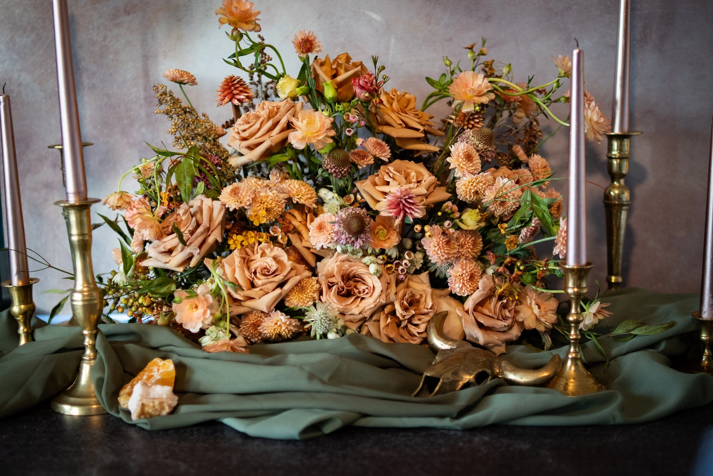 Ash + Ether centerpiece with peach and blush flowers, designed for an elevated Colorado wedding tablescape.