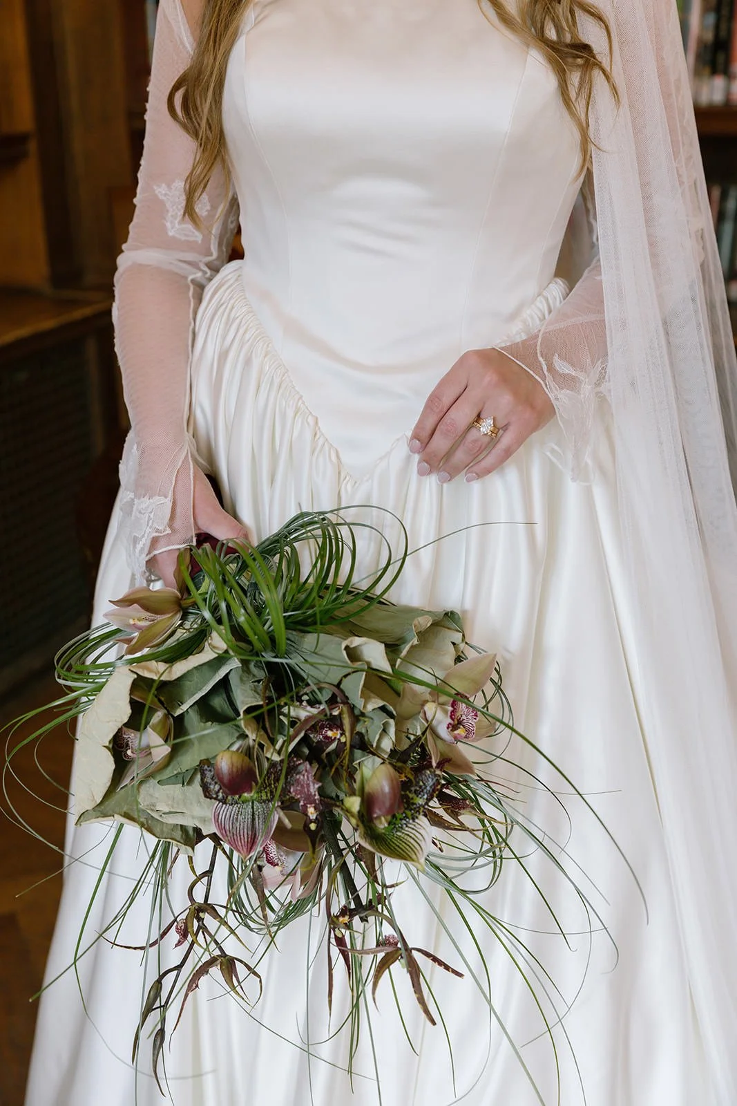 A newlywed in a dress holding a bouquet of flowers with one hand