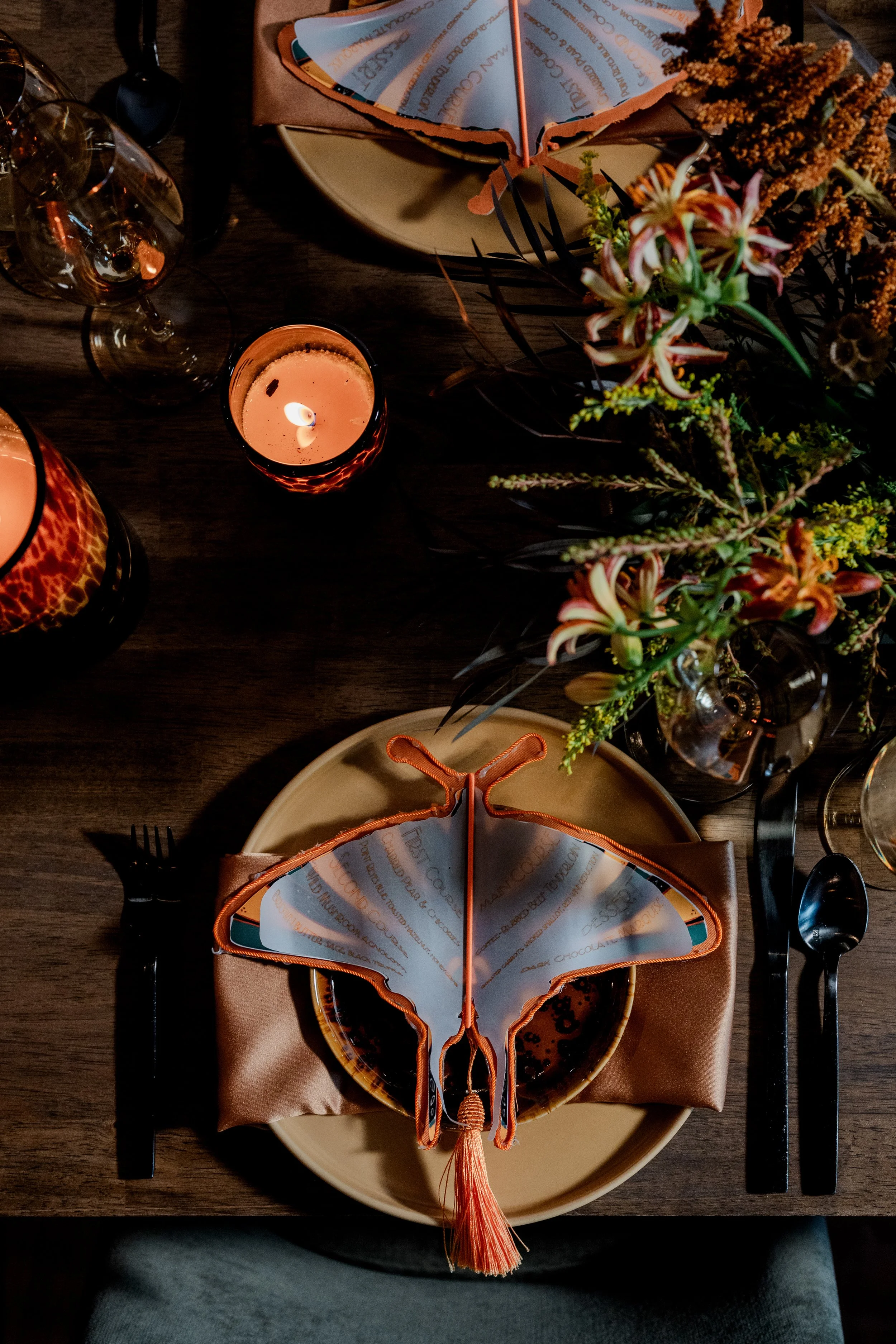 A tablescape with a floral arrangement, flatware, and a butterfly napkin