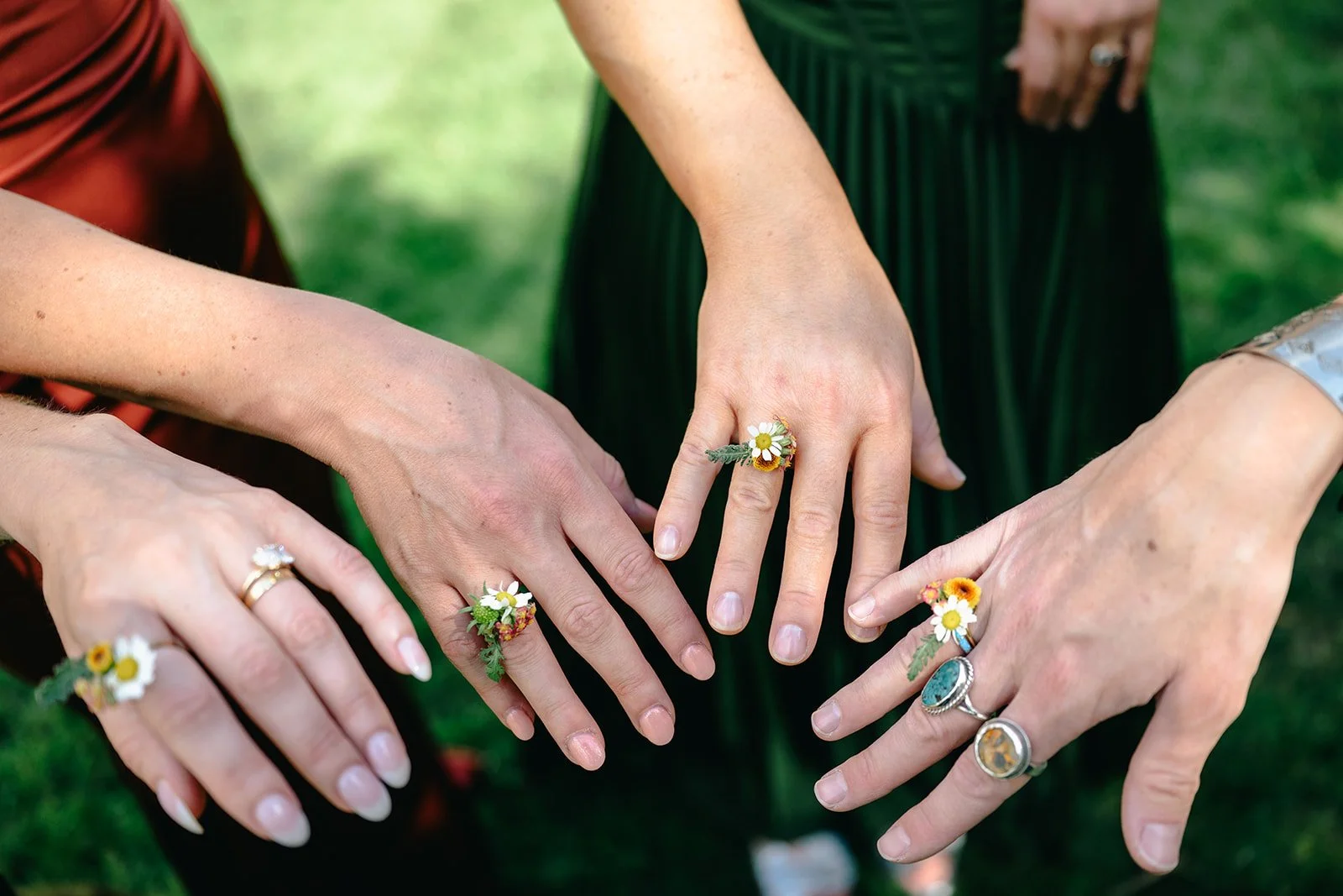 A group of people holding their hands out showing off small rings of flowers