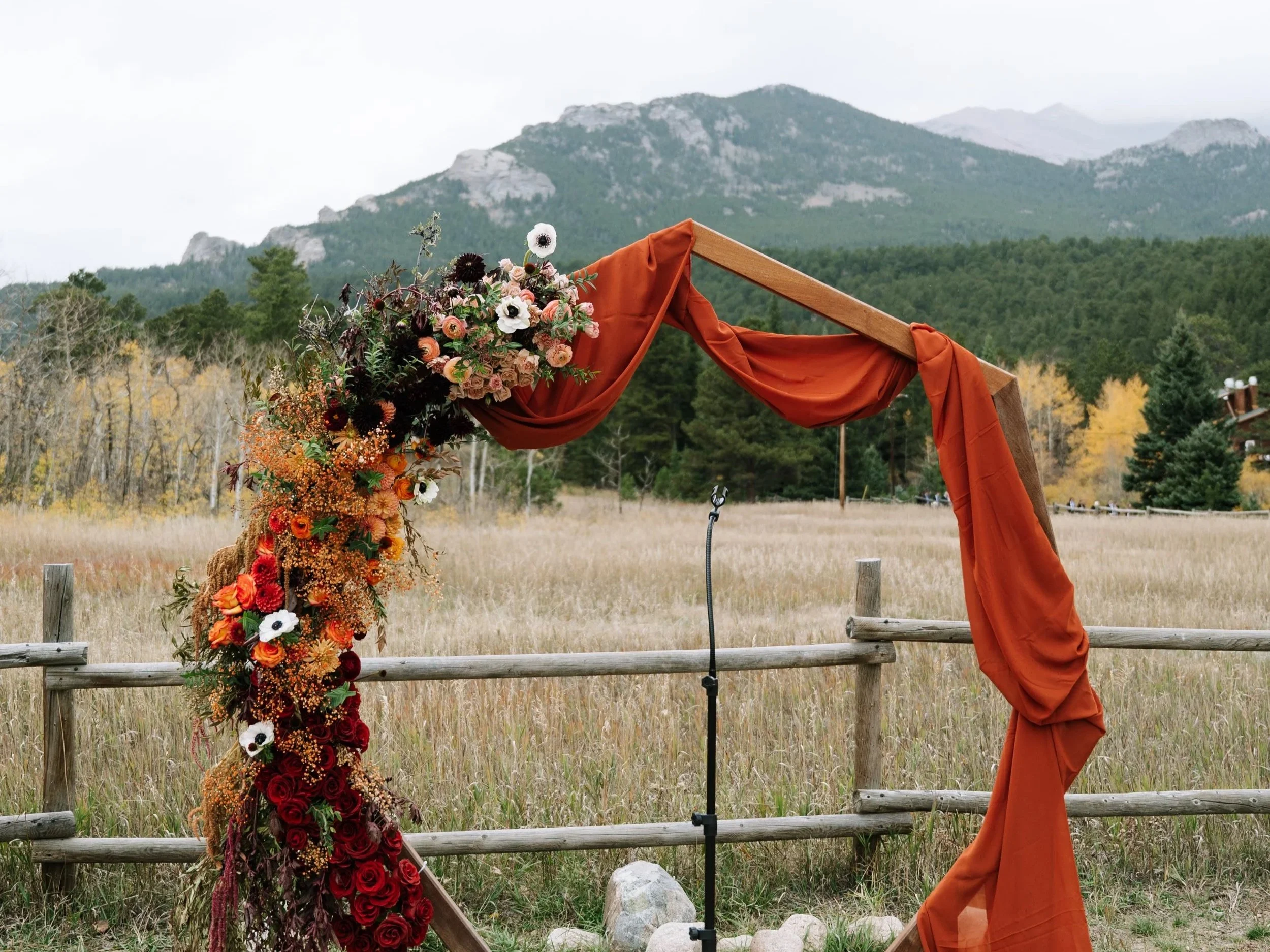 Colorado mountain wedding arch with autumn florals and draped fabric designed by Ash + Ether.