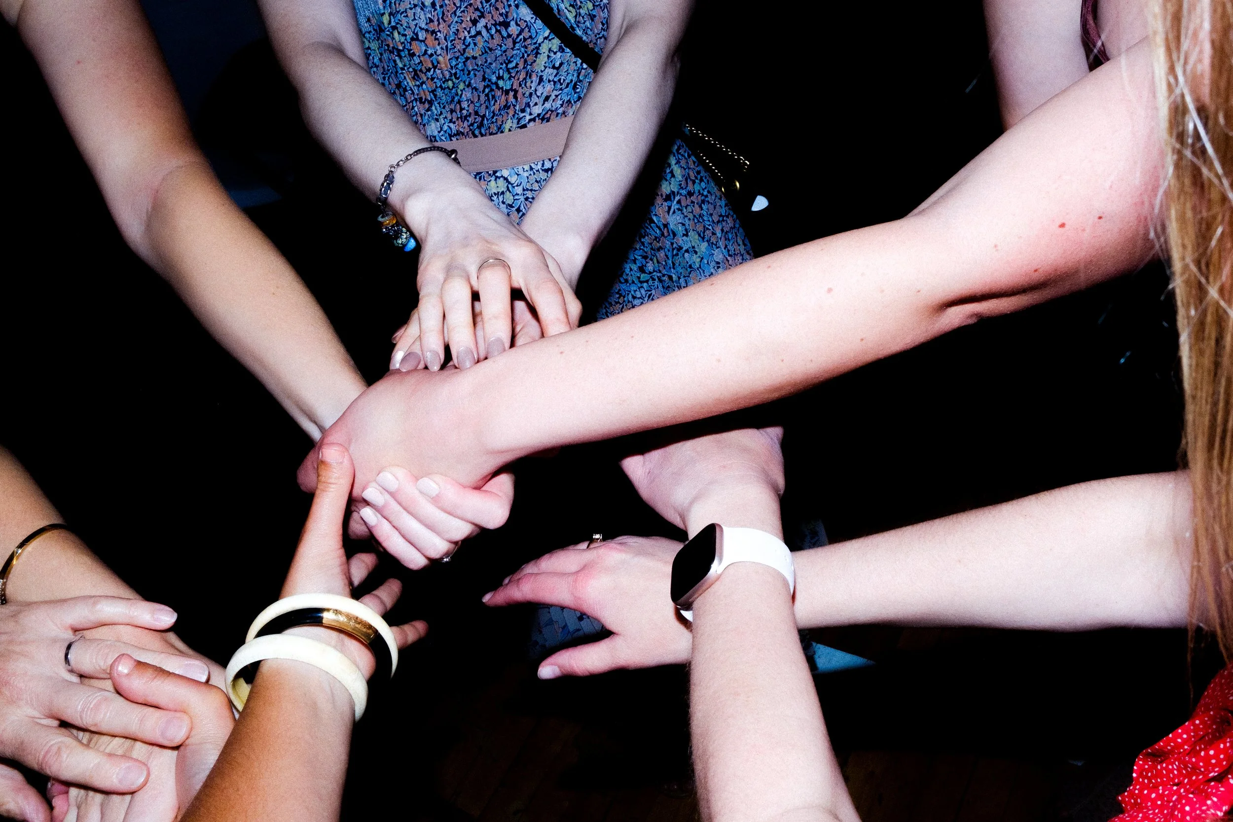 Multiple people's hands stacked together in a show of unity or teamwork.
