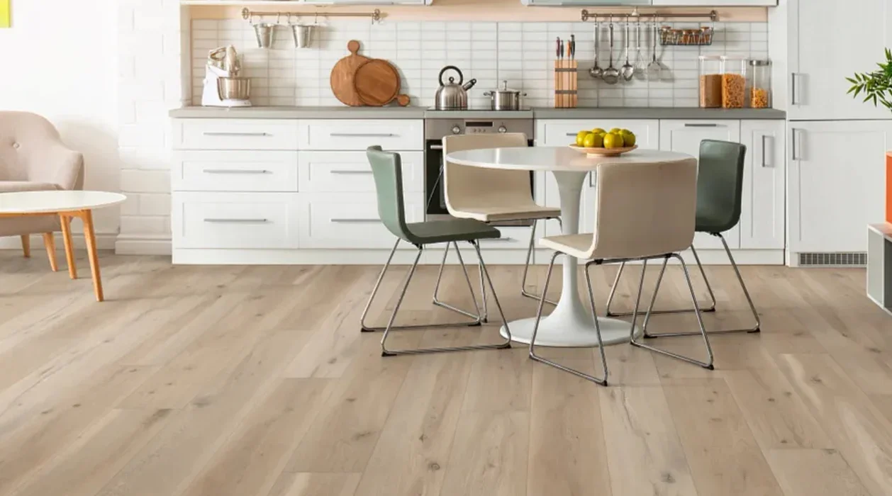 Modern kitchen with white cabinets, a round table with four chairs, and wooden flooring.