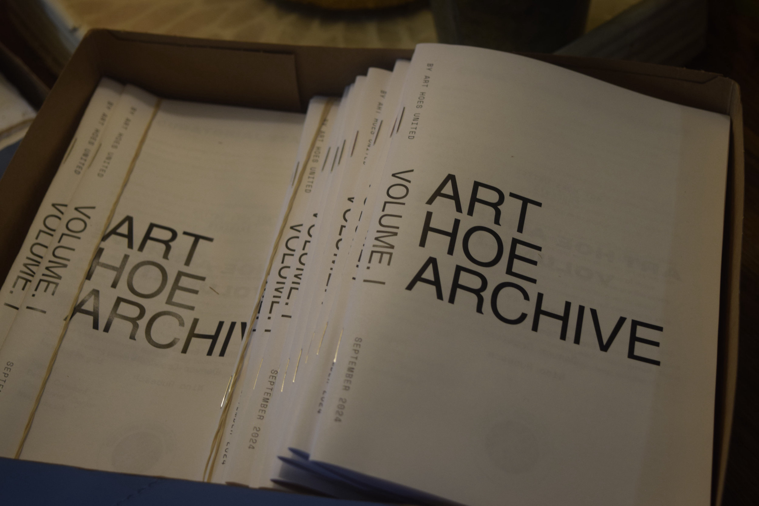 A cardboard box containing printed folders labeled "ART HOE ARCHIVE" with date September 2024.