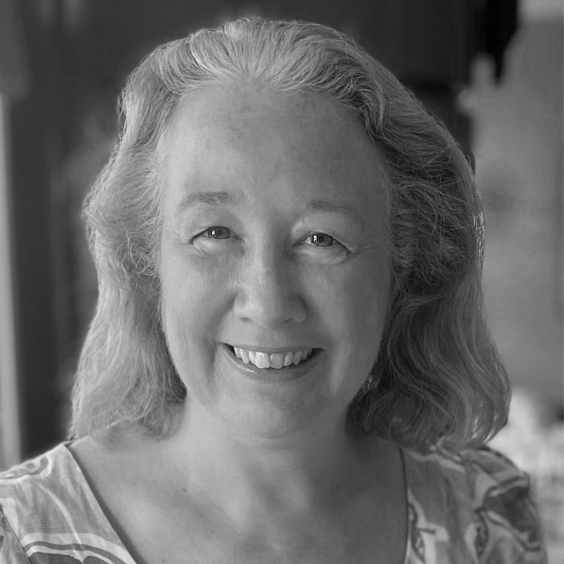 A black and white portrait of a middle-aged woman with wavy hair, smiling at the camera.