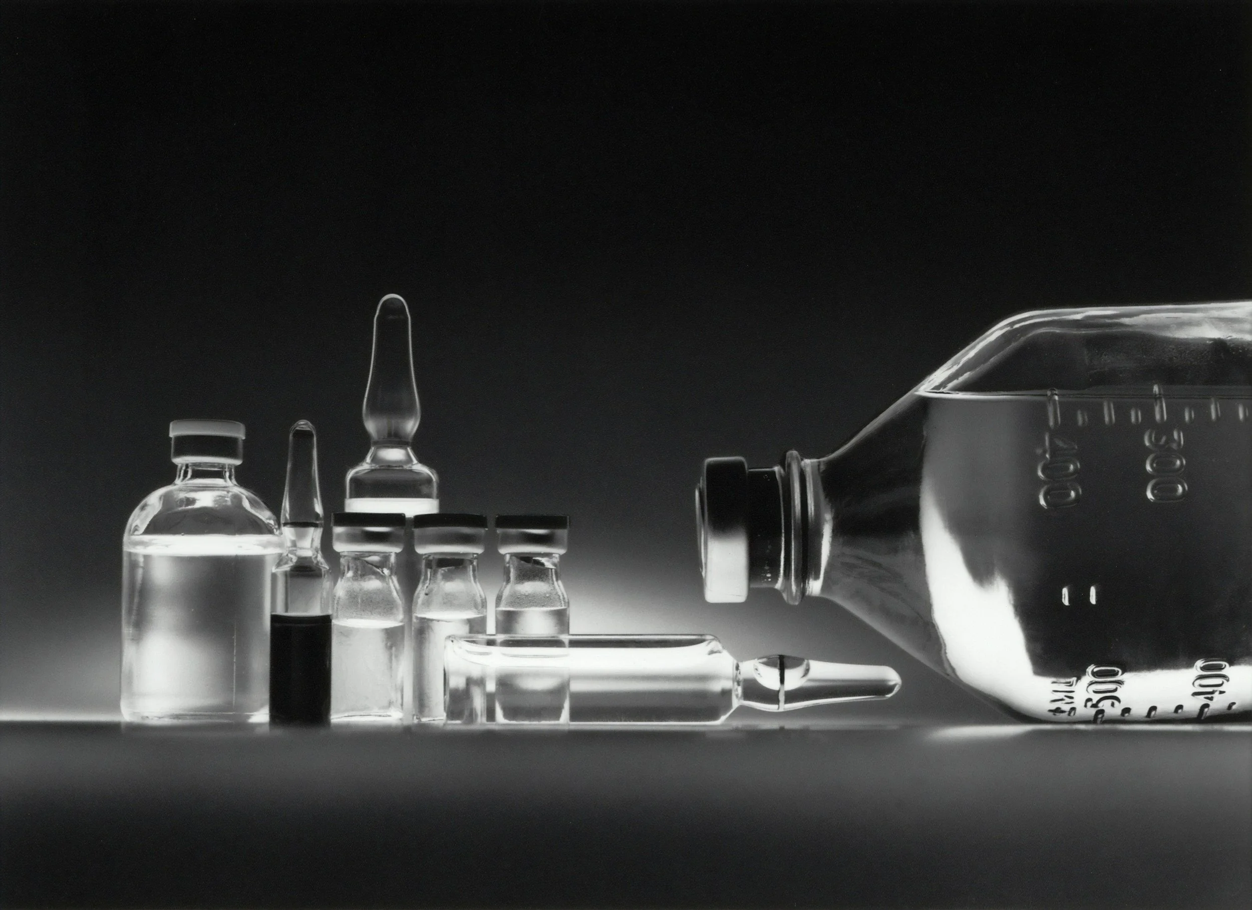 A collection of medicine bottles and syringes arranged on a dark background, with a focus on transparency and reflections.