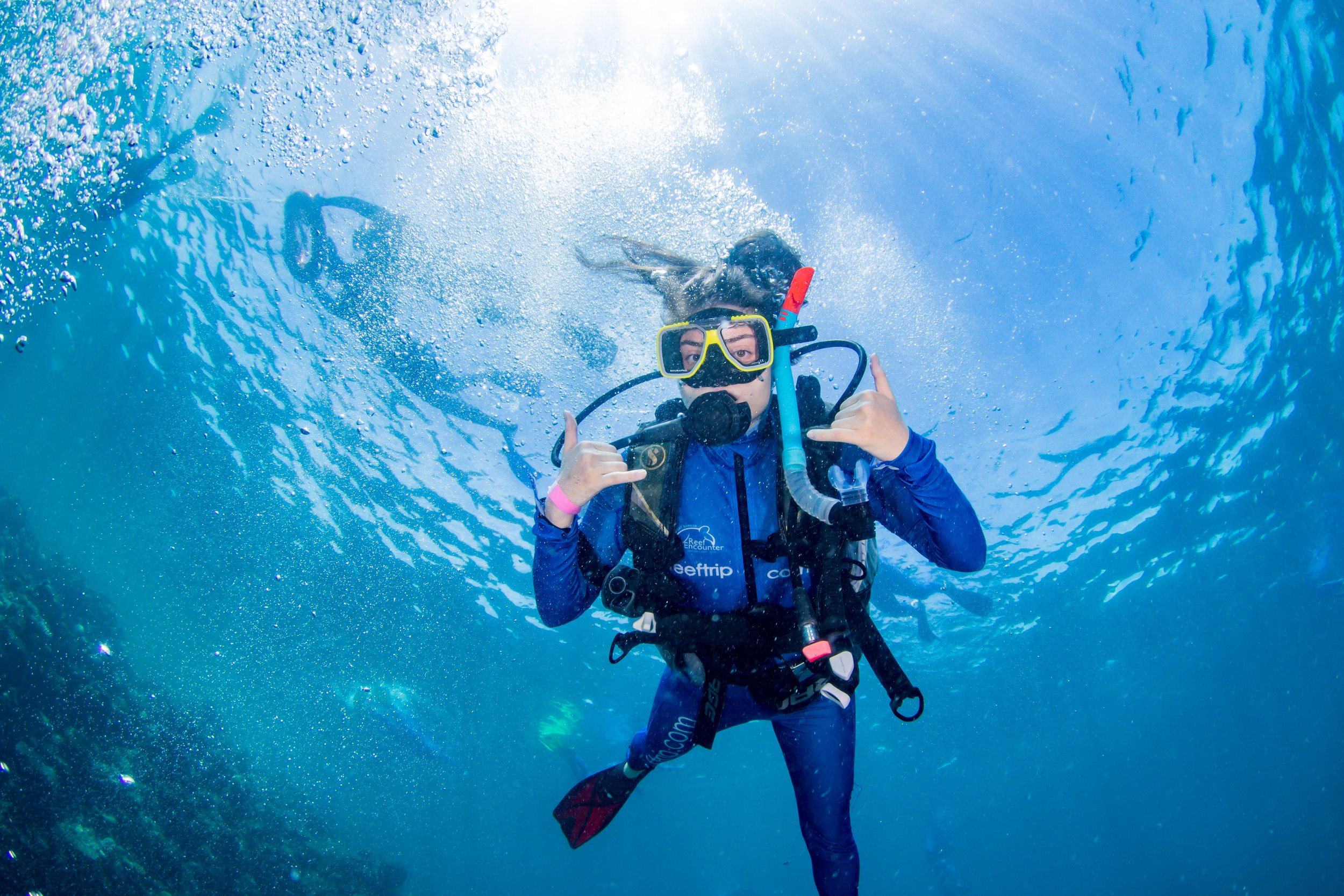 Ayșenur Ezgi Eygi scuba diving underwater, wearing a wetsuit, mask, and snorkel, giving a thumbs-up sign.