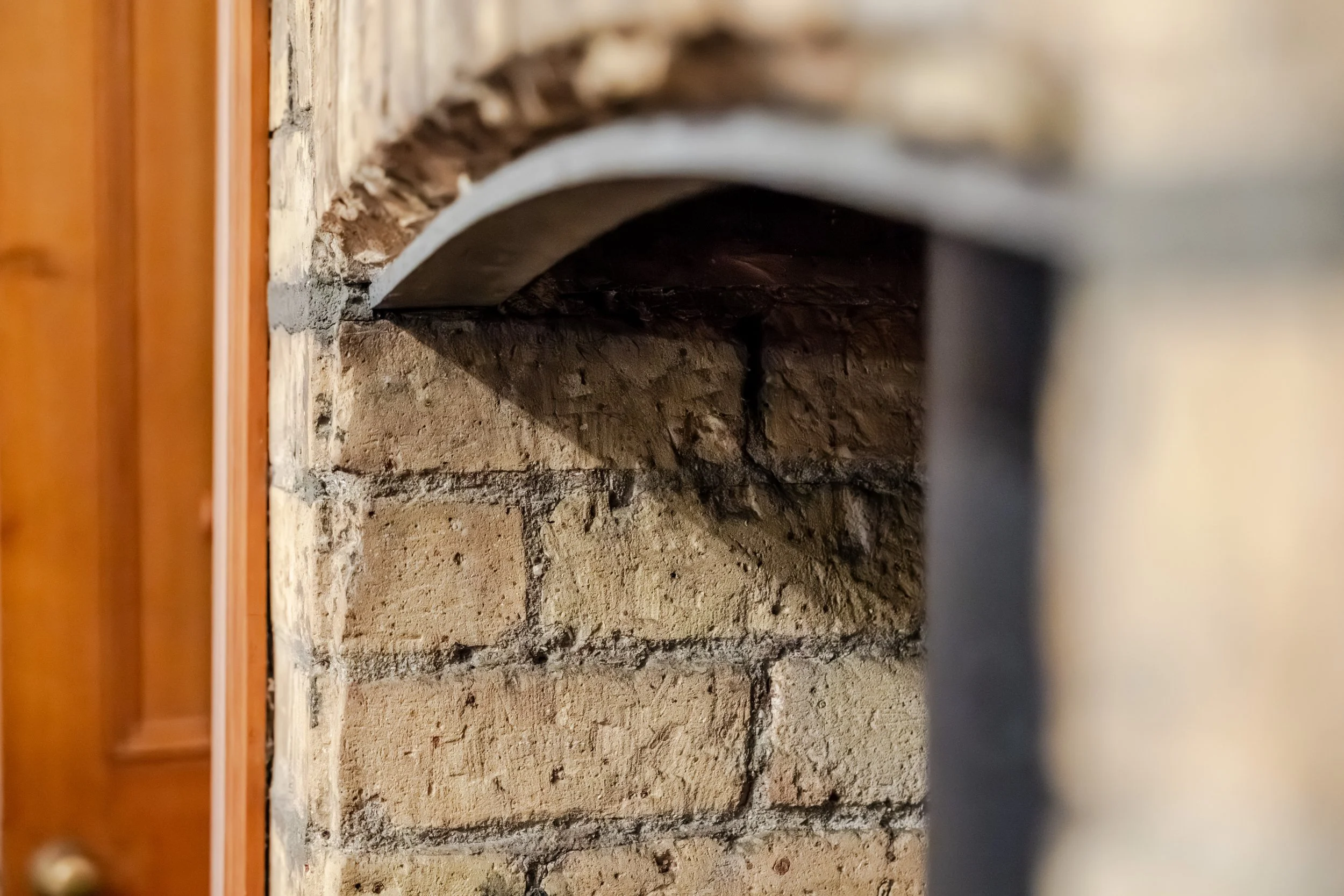 Close-up of a brick fireplace with a dark opening and a white arched trim.